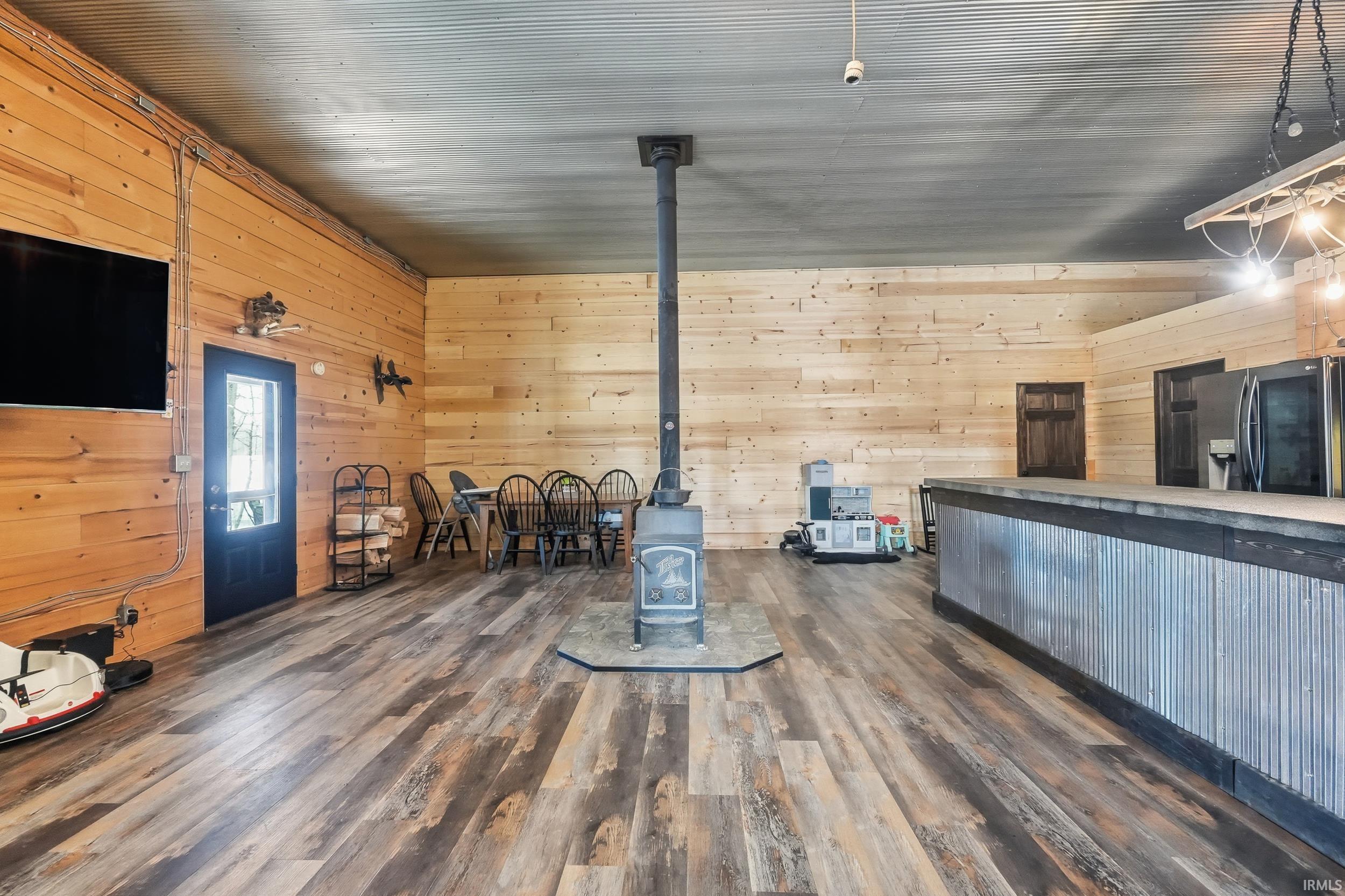 Living area with wooden walls, a wood stove, and dark wood-style floors