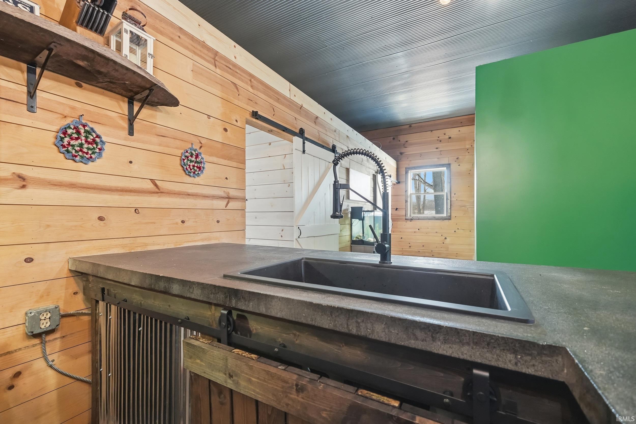Kitchen featuring wooden walls, a barn door, and dark countertops