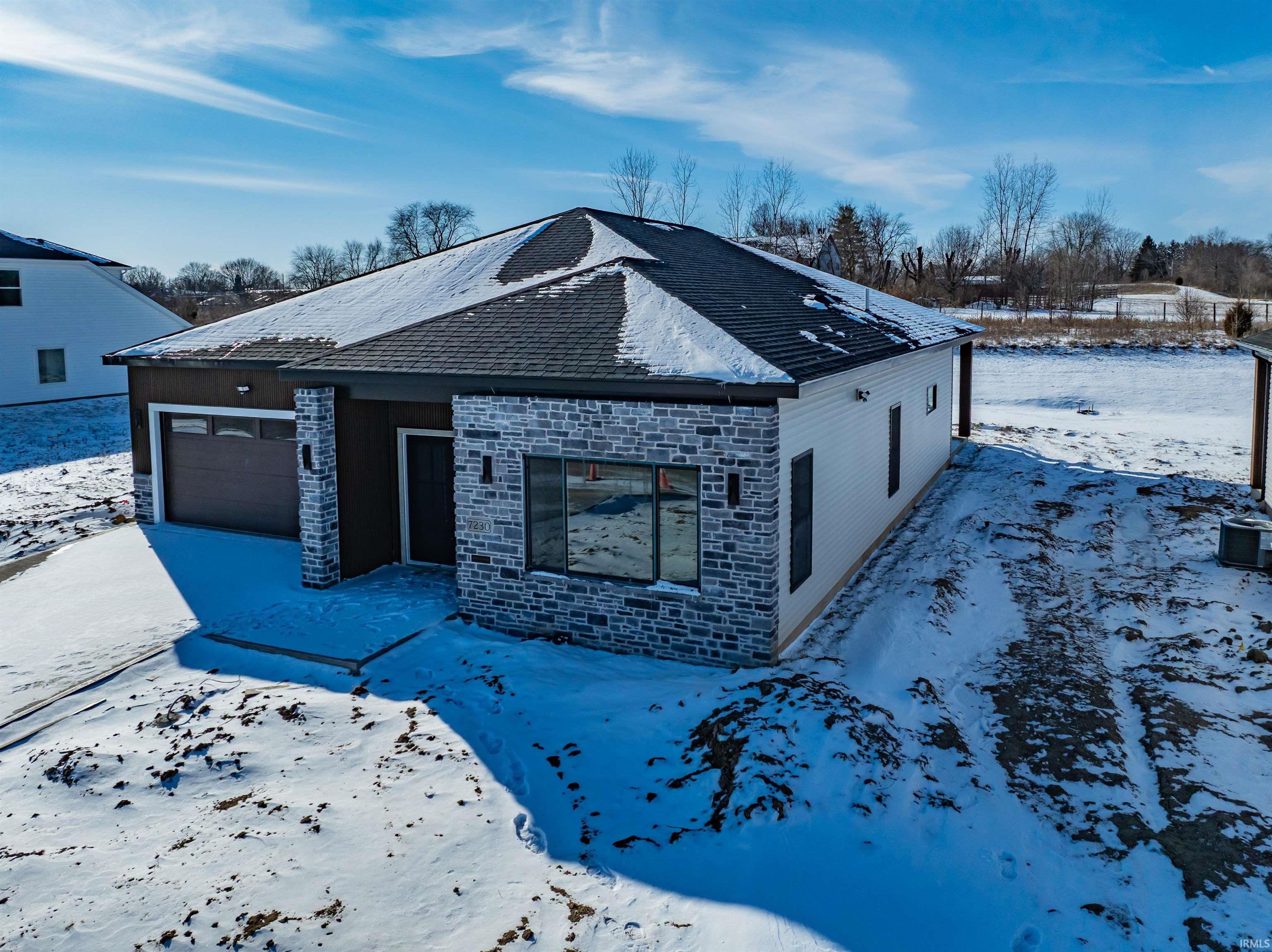 View of front of home featuring stone siding, an attached garage, driveway, and roof with shingles