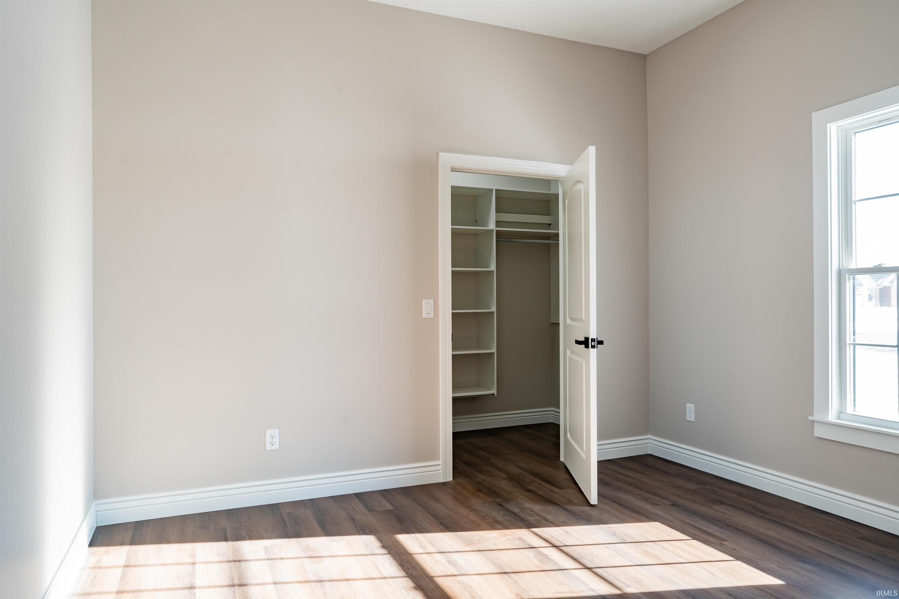 Unfurnished bedroom with dark wood-style flooring and a spacious closet