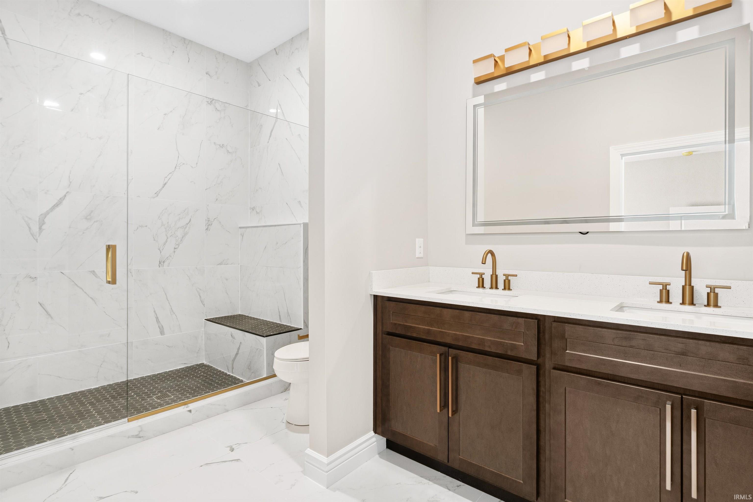 Full bathroom featuring light marble finish flooring, double vanity, and a marble finish shower