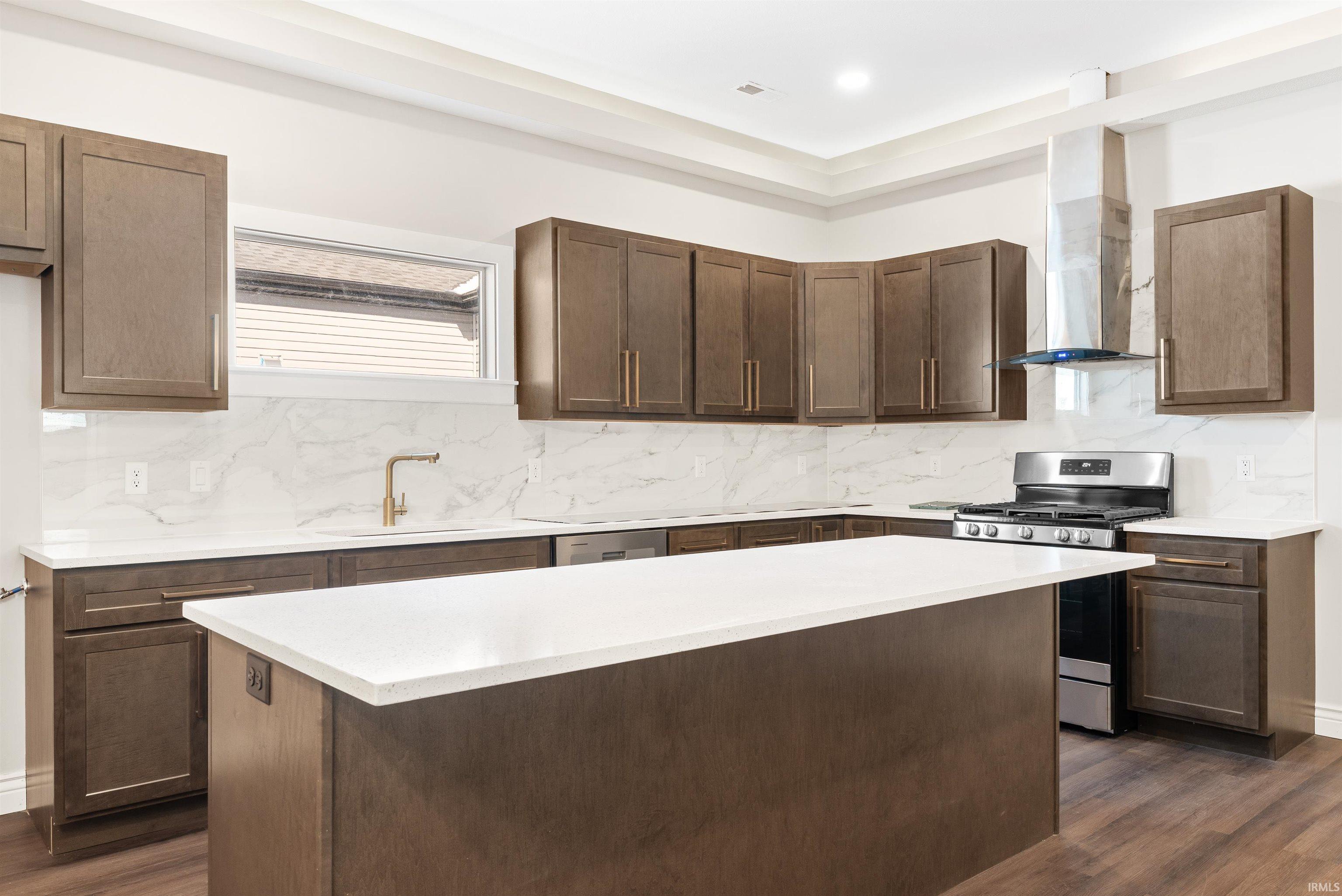 Kitchen featuring stainless steel gas range, decorative backsplash, dark wood-type flooring, a center island, and dark brown cabinets