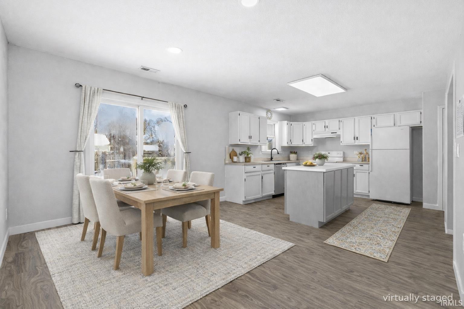 Kitchen featuring white appliances, a center island, light countertops, white cabinets, and dark wood-style floors