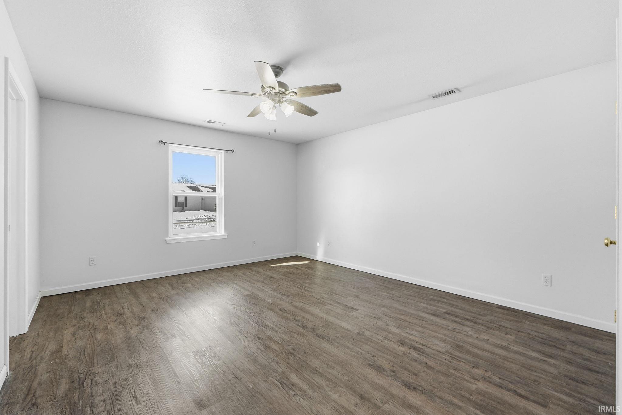 Unfurnished room with dark wood-style floors and ceiling fan