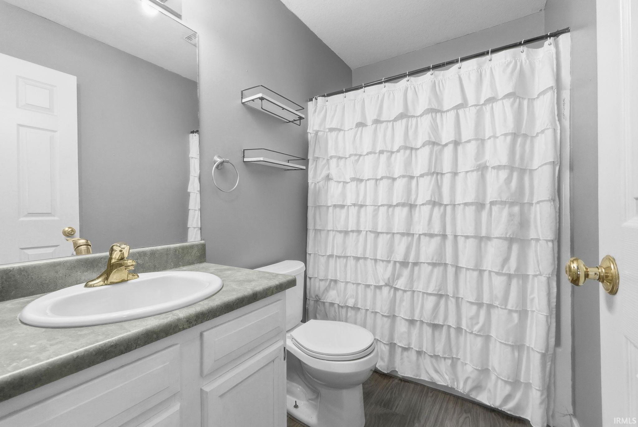 Full bath featuring curtained shower, vanity, and dark wood finished floors