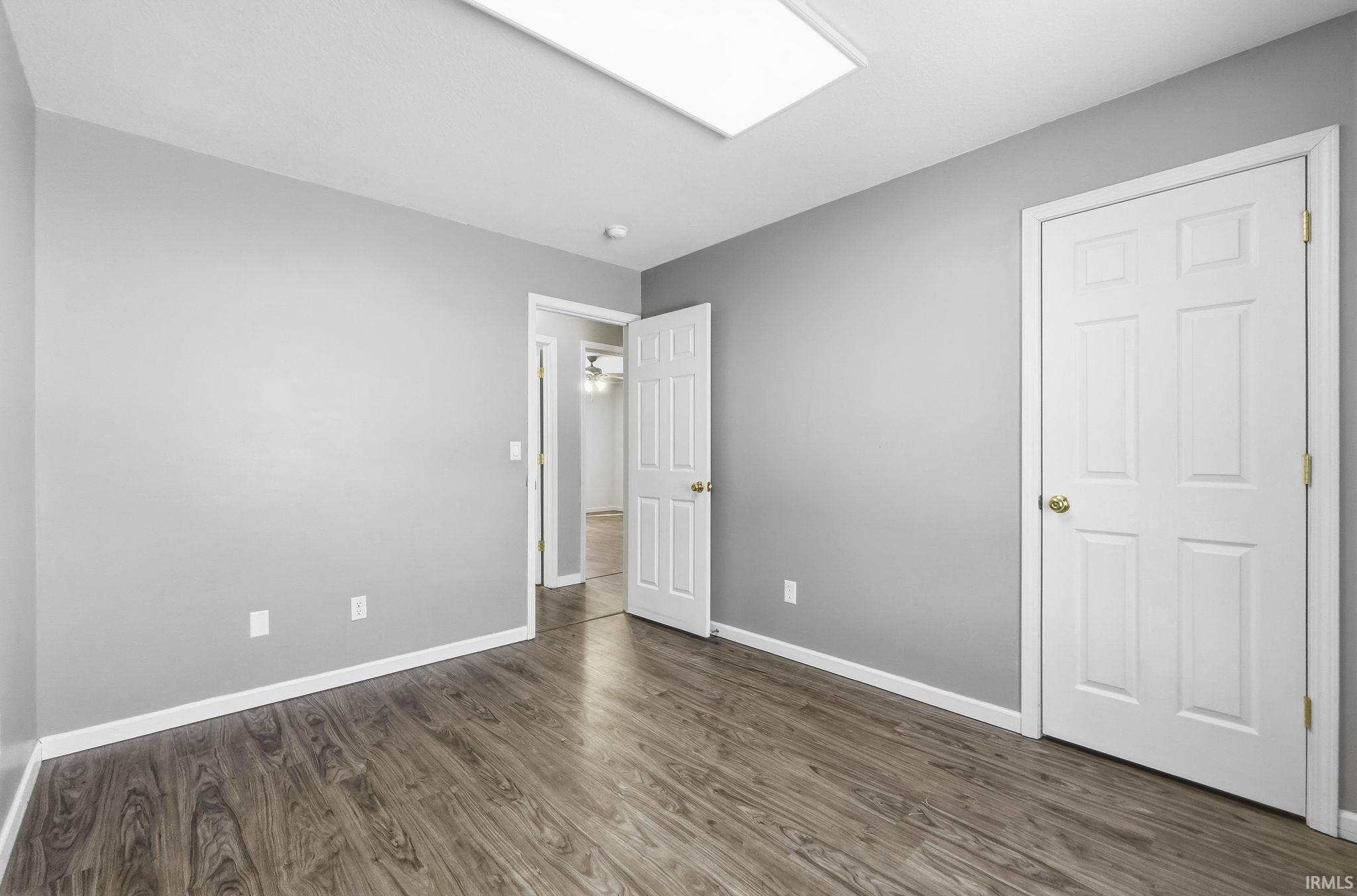 Unfurnished bedroom with dark wood finished floors and baseboards