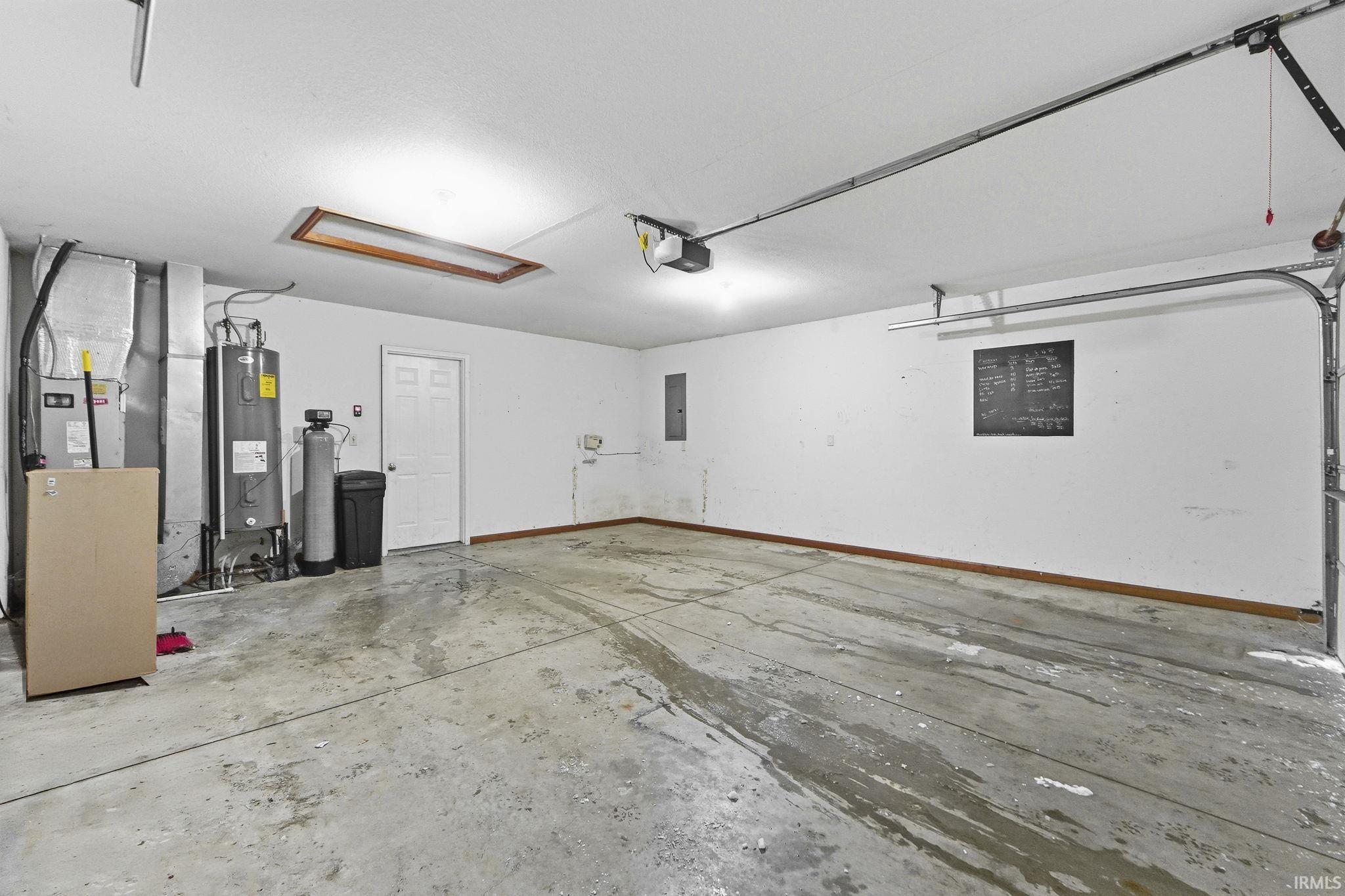 Garage featuring heating unit, water heater, and electric panel