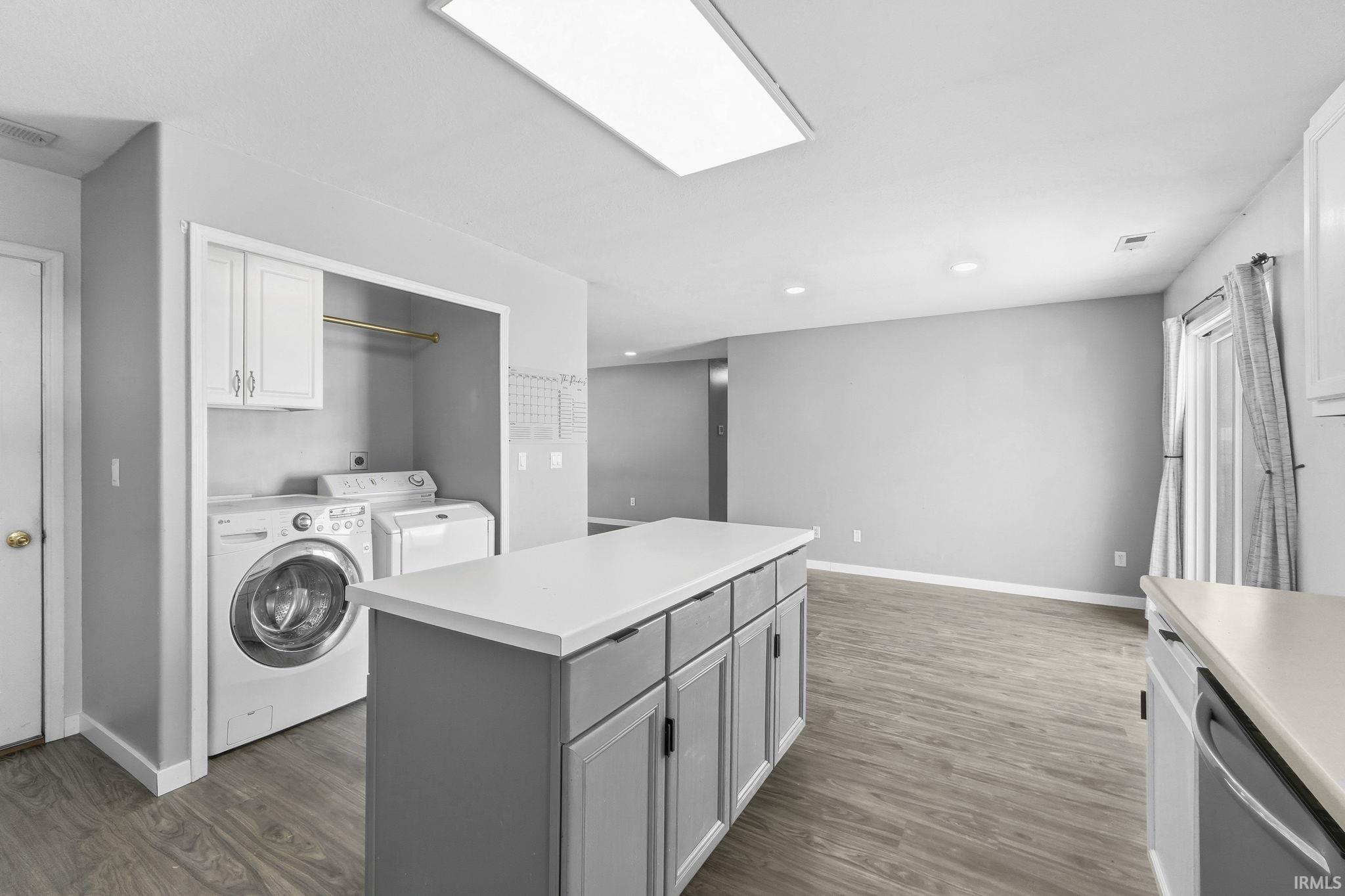 Laundry area featuring dark wood finished floors, washer and dryer, and recessed lighting