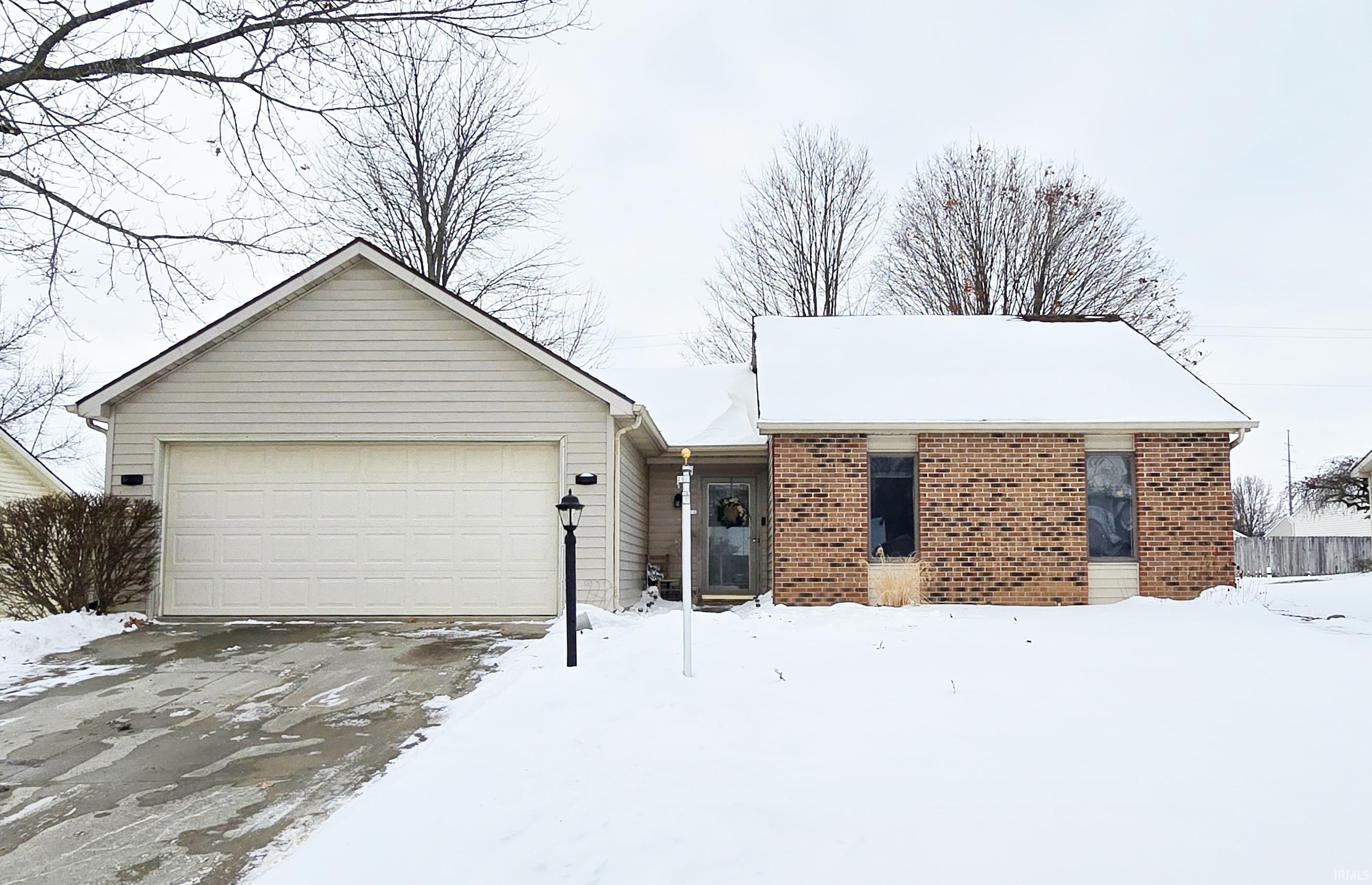 Ranch-style house featuring brick siding, an attached garage, and concrete driveway