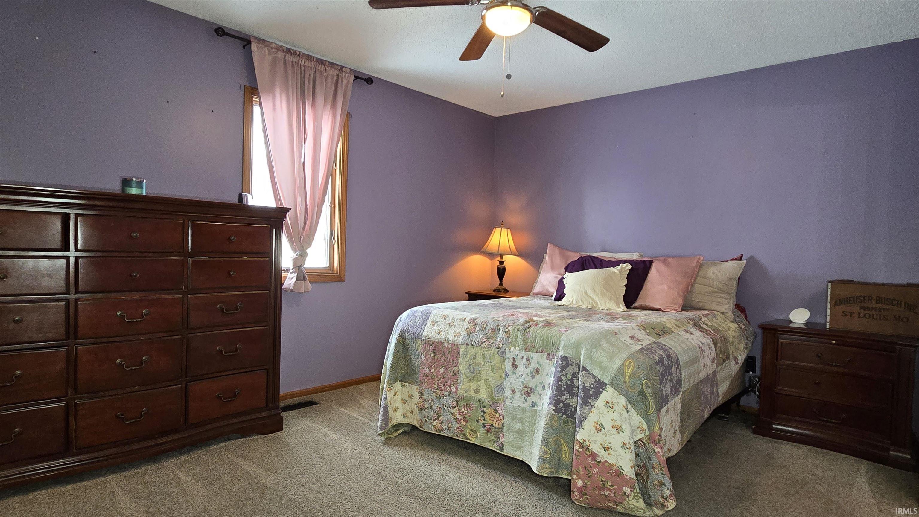 Carpeted bedroom with a ceiling fan and baseboards