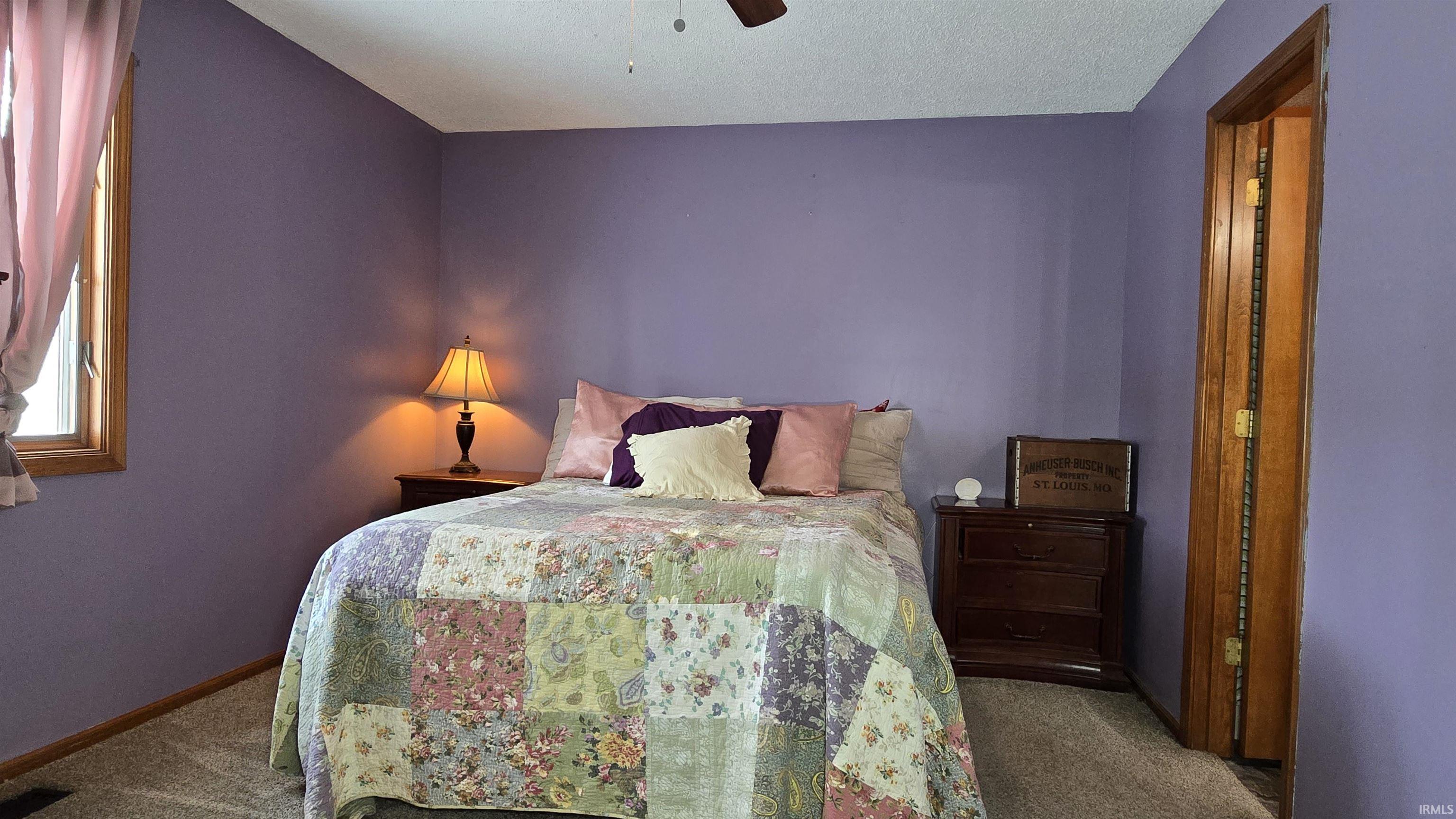 Carpeted bedroom featuring a ceiling fan and a textured ceiling