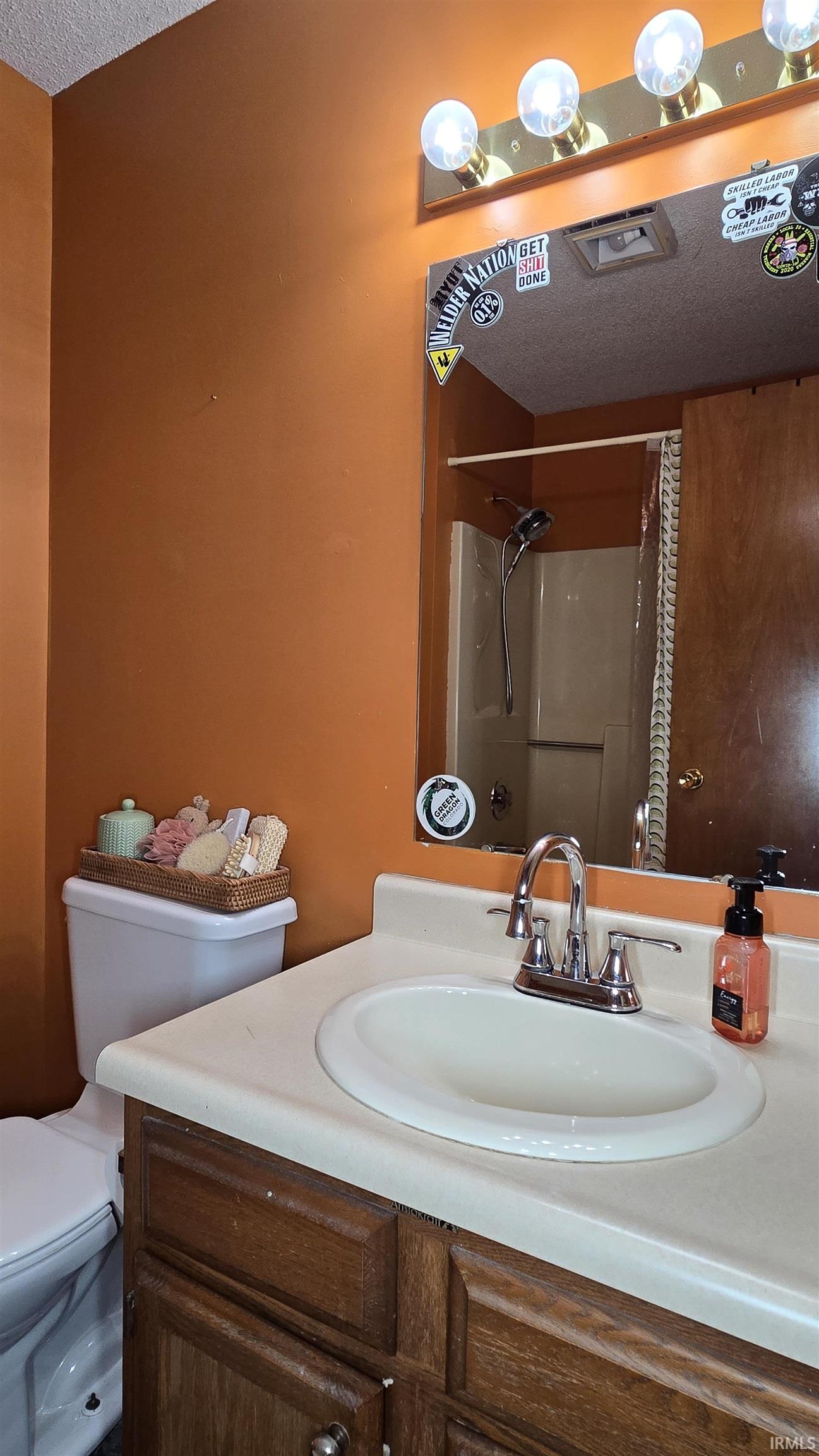 Full bathroom with curtained shower, a textured ceiling, and vanity