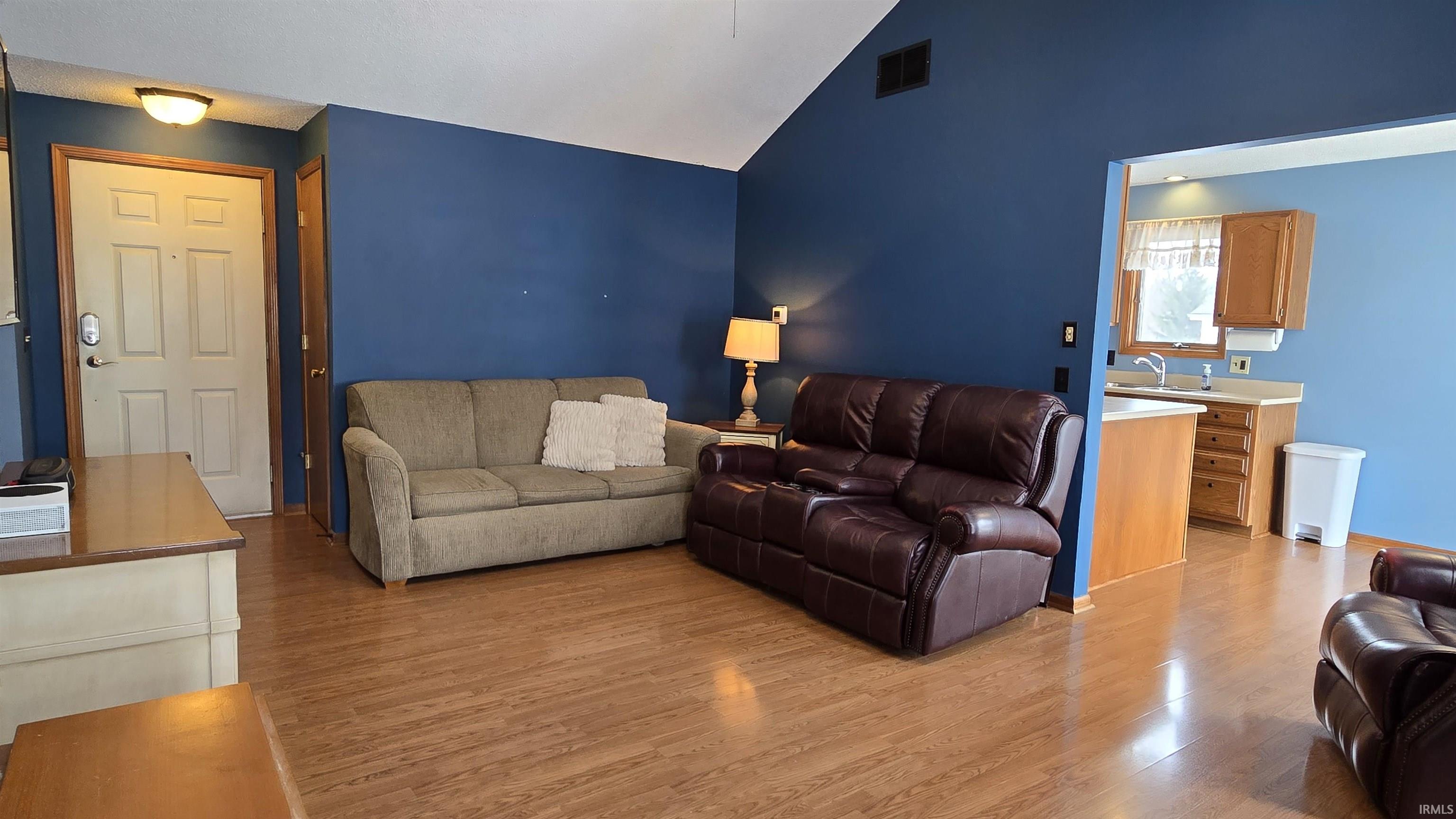 Living area featuring light wood finished floors and high vaulted ceiling