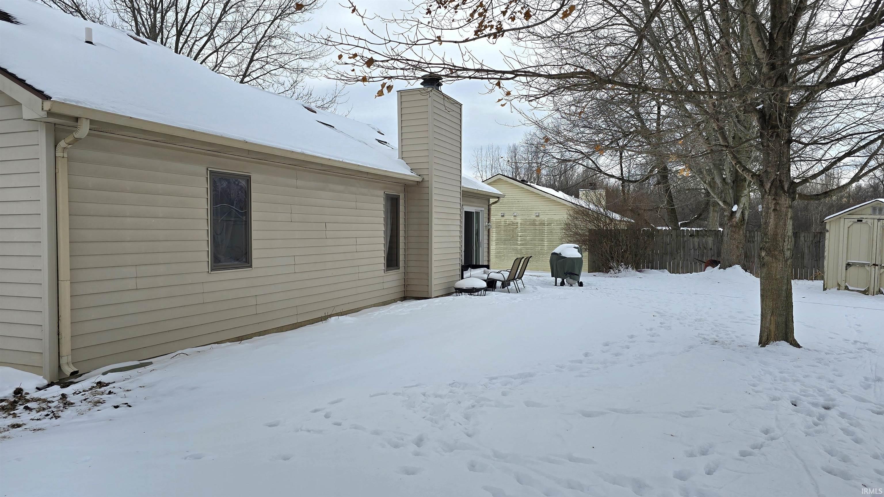 Yard layered in snow with a storage shed