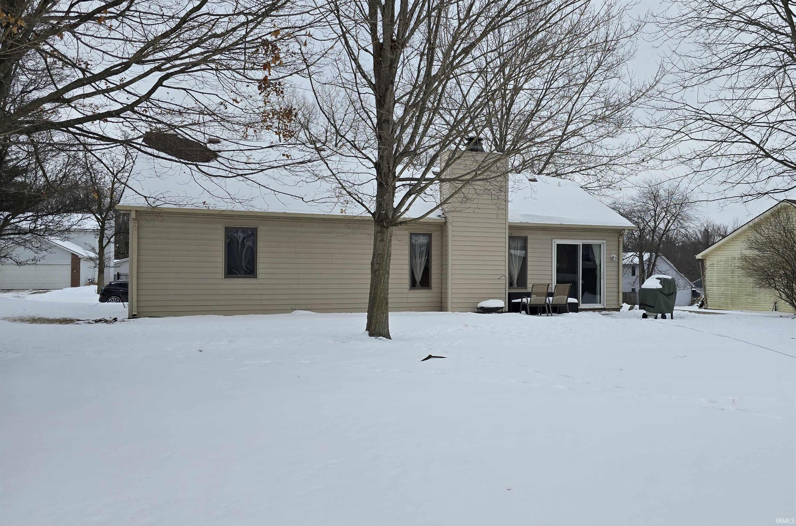 Snow covered property with a chimney and a patio area