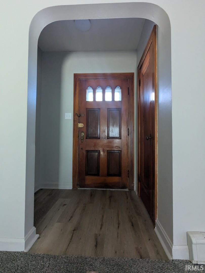 Foyer featuring arched walkways and wood finished floors