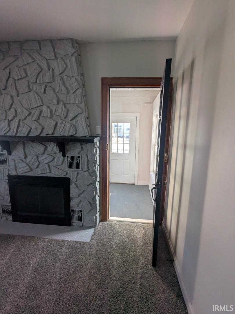 Unfurnished living room featuring carpet floors and a fireplace