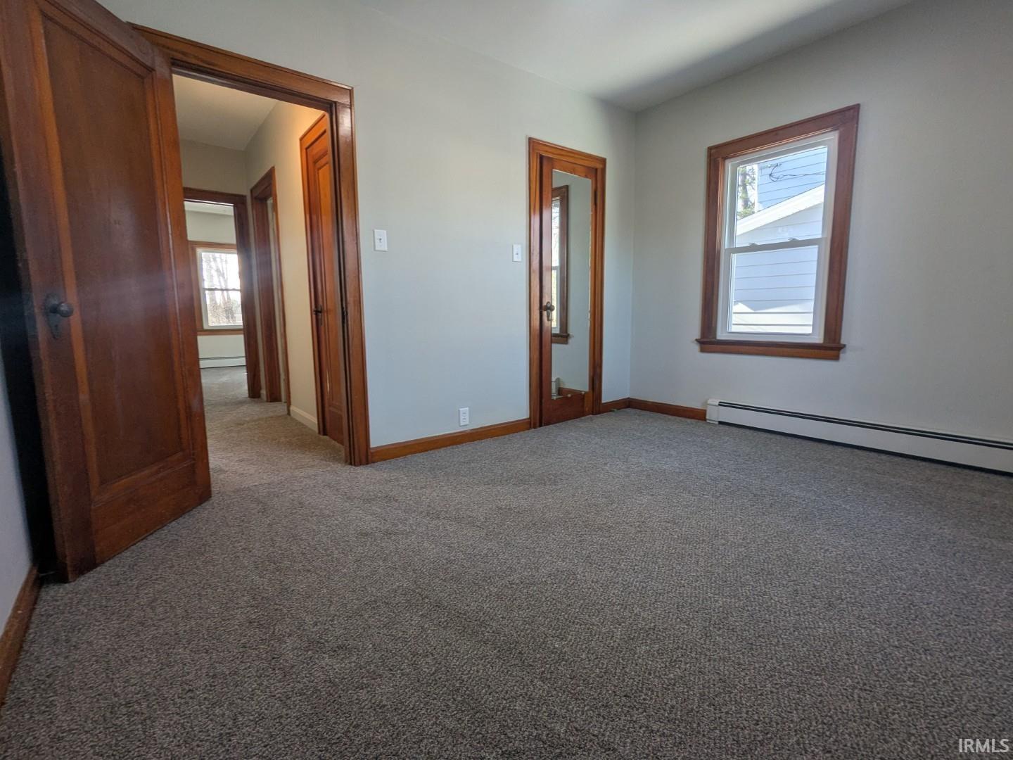 Unfurnished bedroom featuring carpet flooring and a baseboard radiator