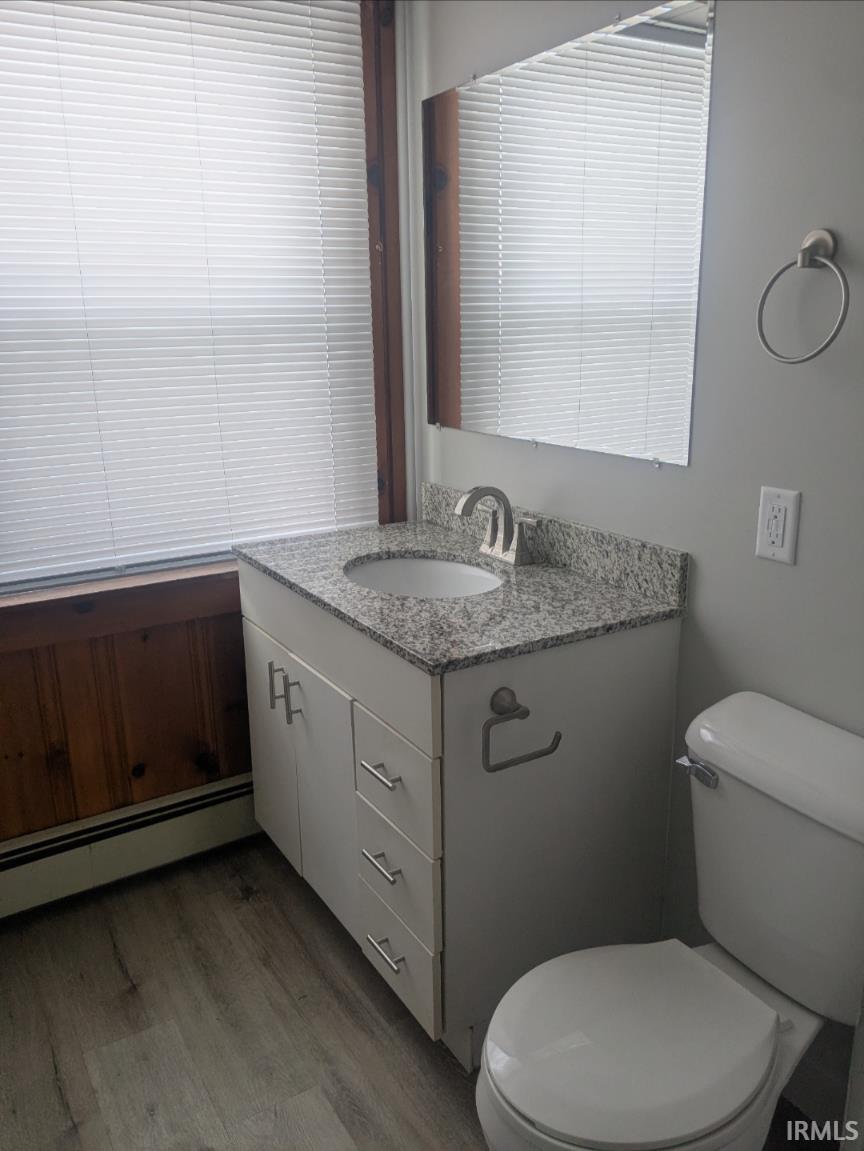 Half bathroom with vanity, baseboard heating, and light wood finished floors