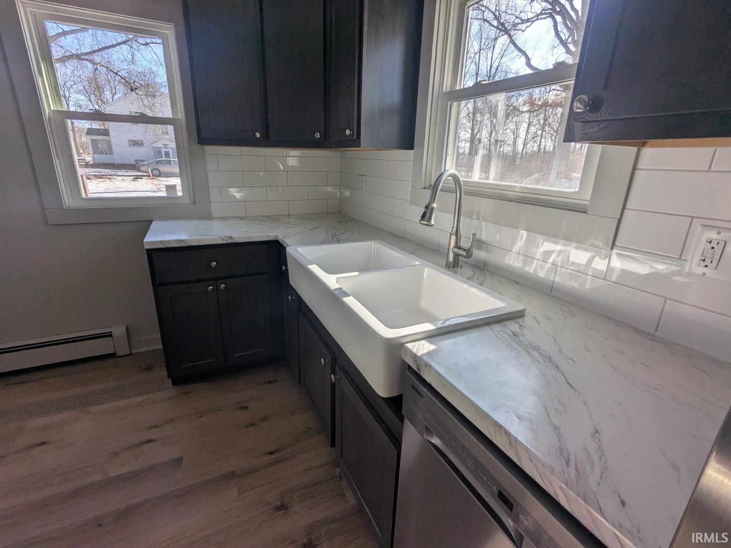 Kitchen featuring stainless steel dishwasher, dark wood finished floors, decorative backsplash, and plenty of natural light
