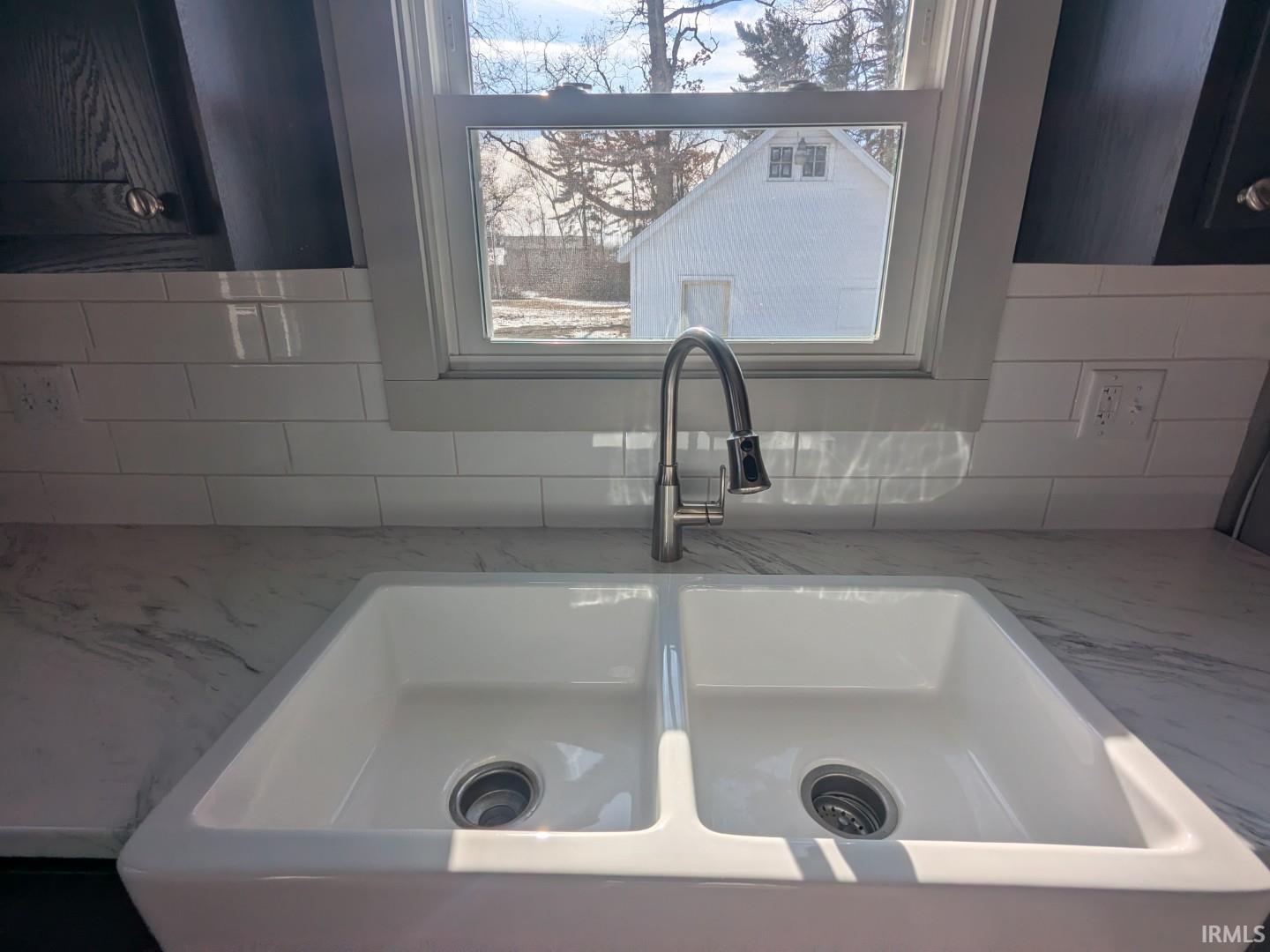 Kitchen view of a sink and light stone counters