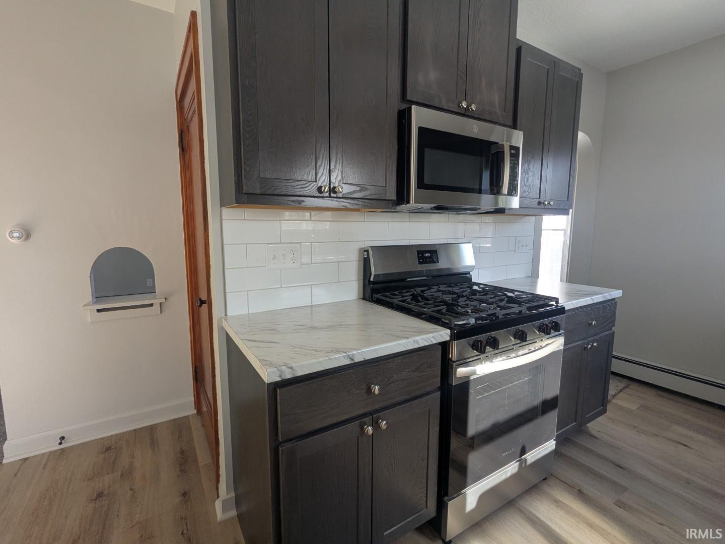 Kitchen featuring stainless steel appliances, decorative backsplash, and light wood-style flooring