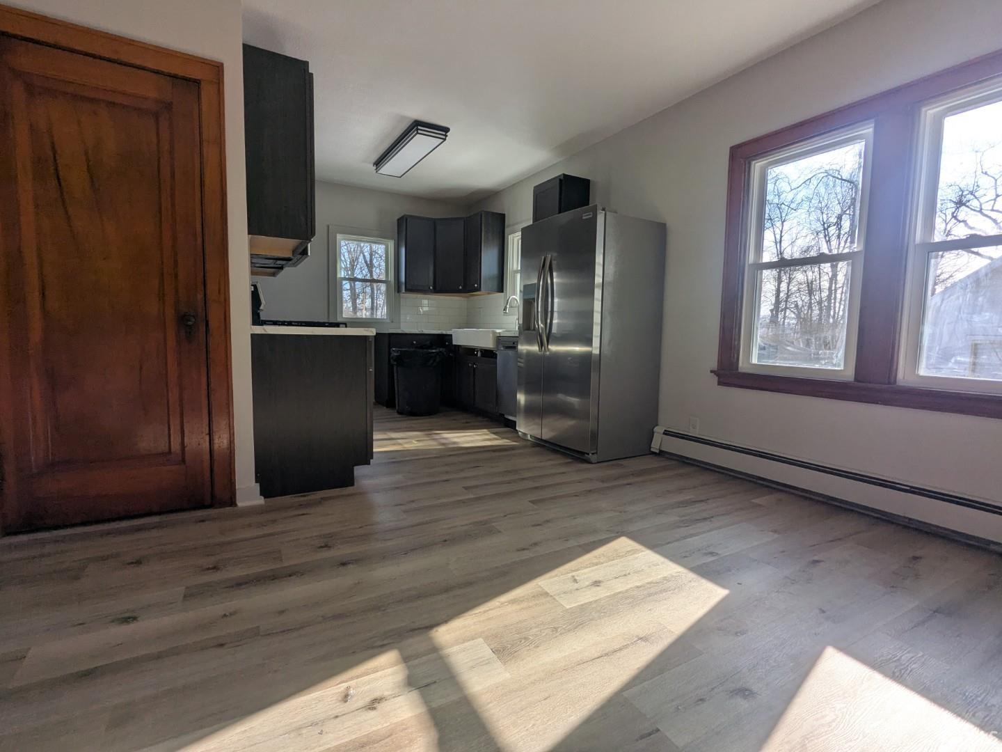 Kitchen featuring appliances with stainless steel finishes, light wood-style flooring, light countertops, and tasteful backsplash