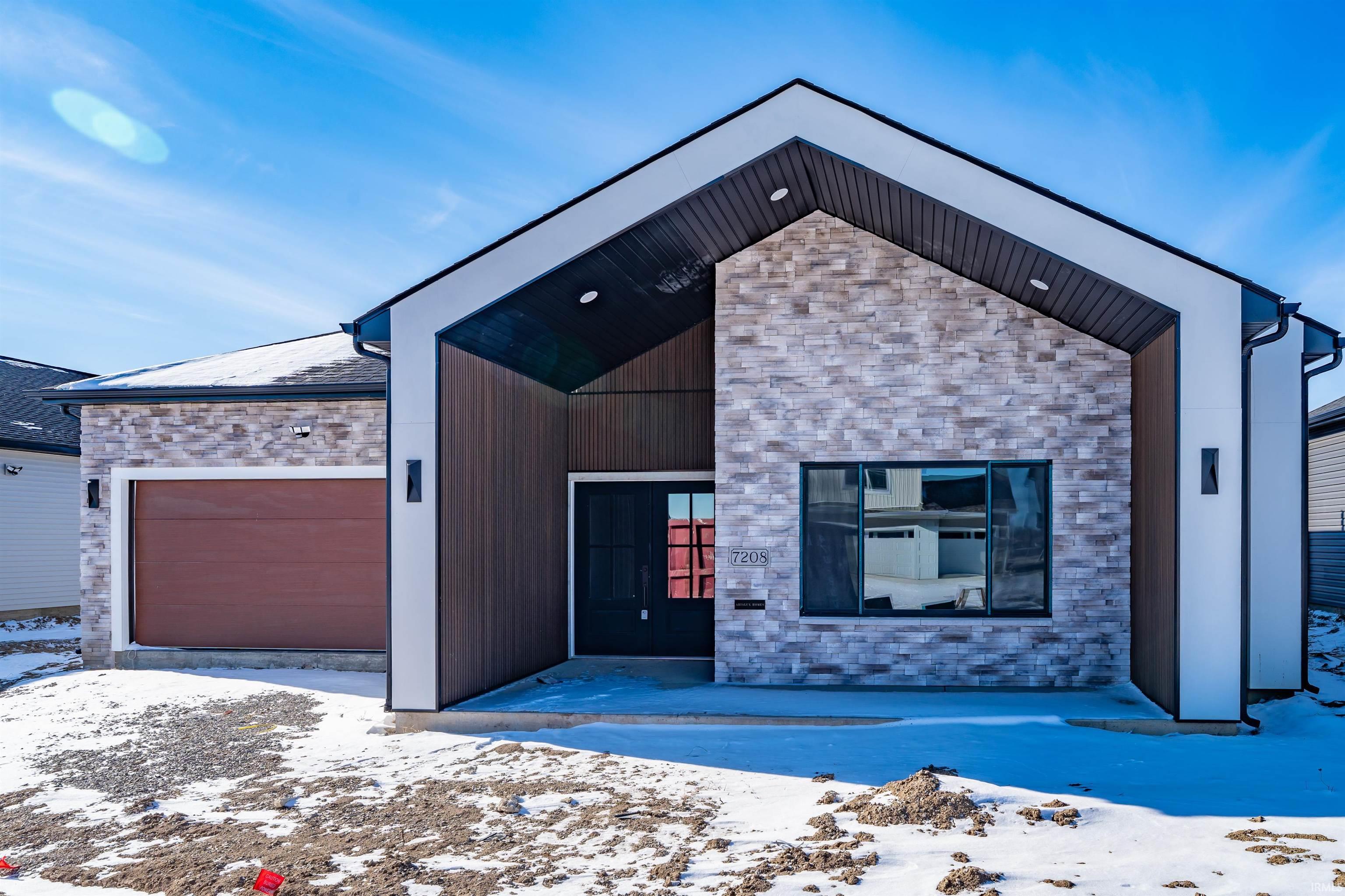 Contemporary home featuring stone siding and a garage