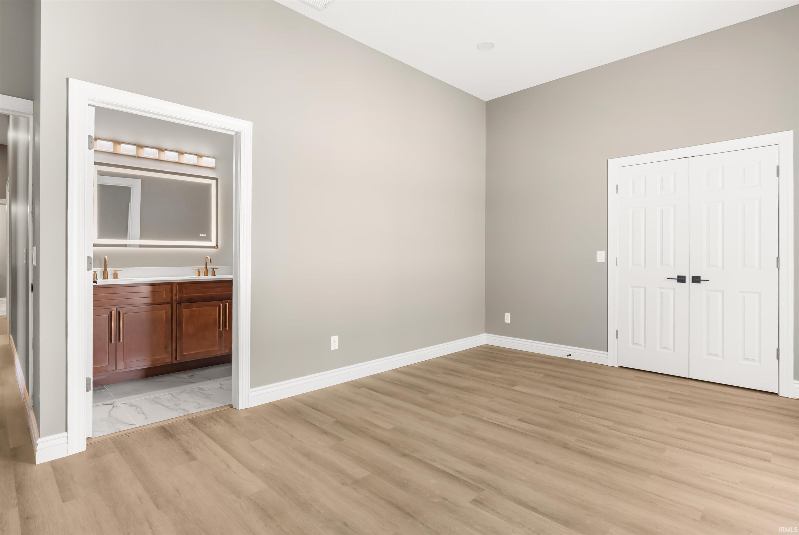 Unfurnished bedroom featuring a closet, light wood-style flooring, and ensuite bathroom