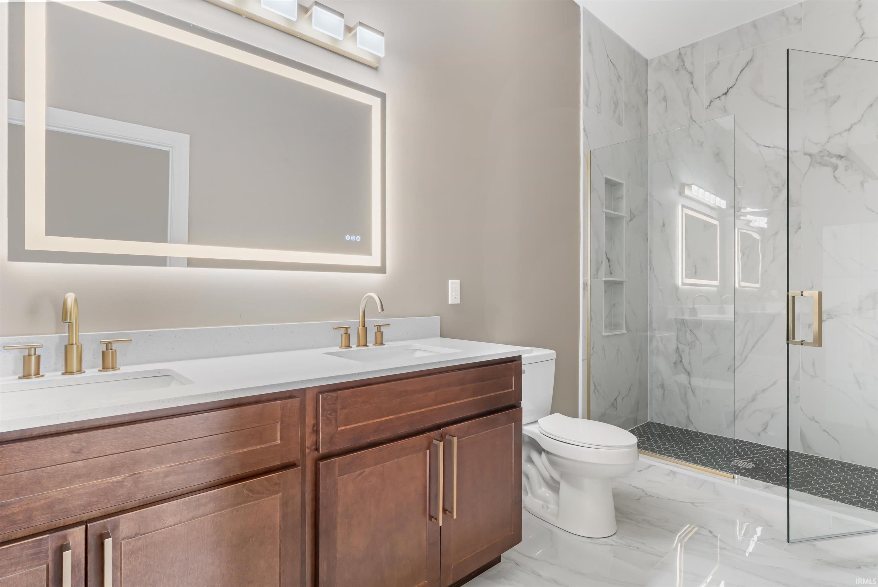 Full bathroom featuring light marble finish flooring, double vanity, and a marble finish shower