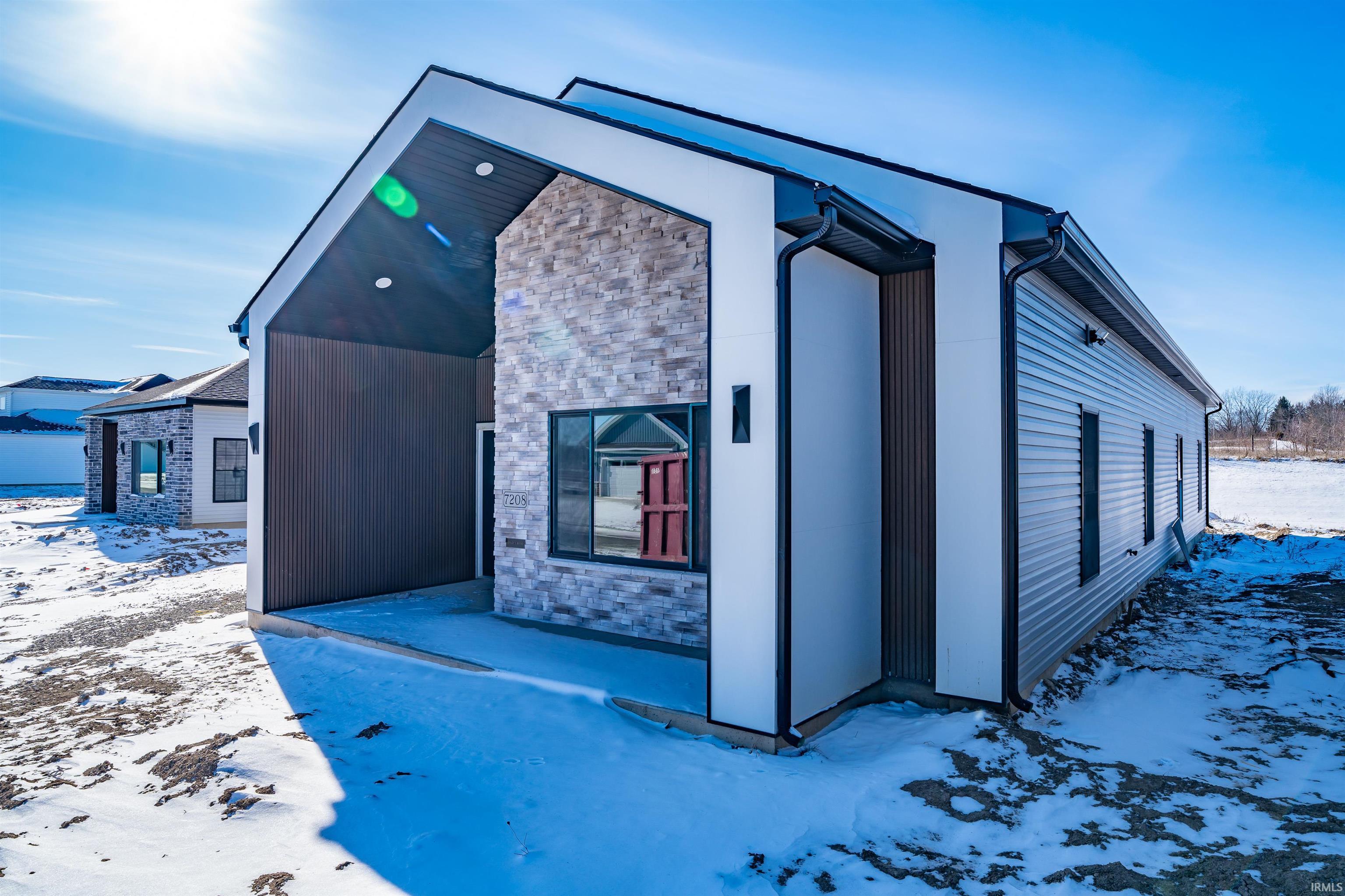 Snow covered property with stone siding