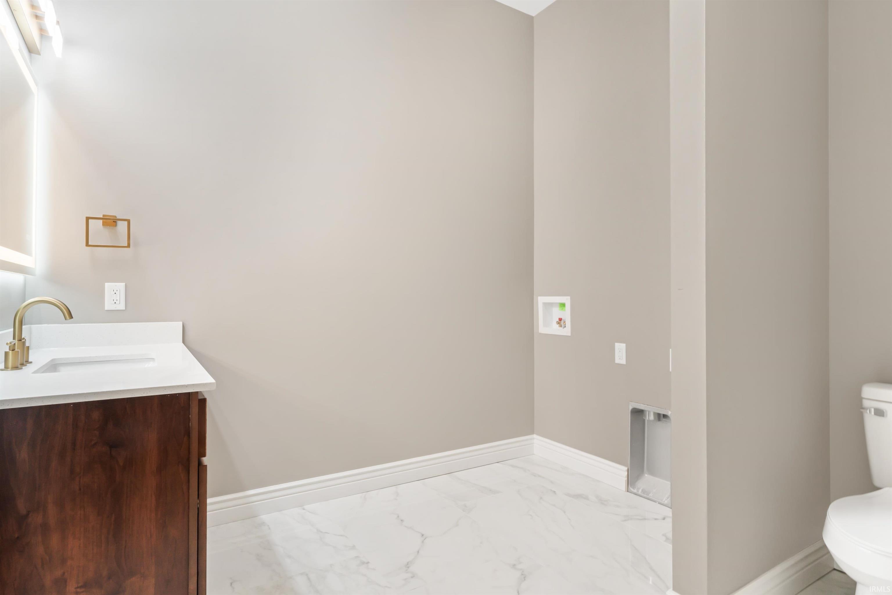 Half bath with vanity and marble finish flooring