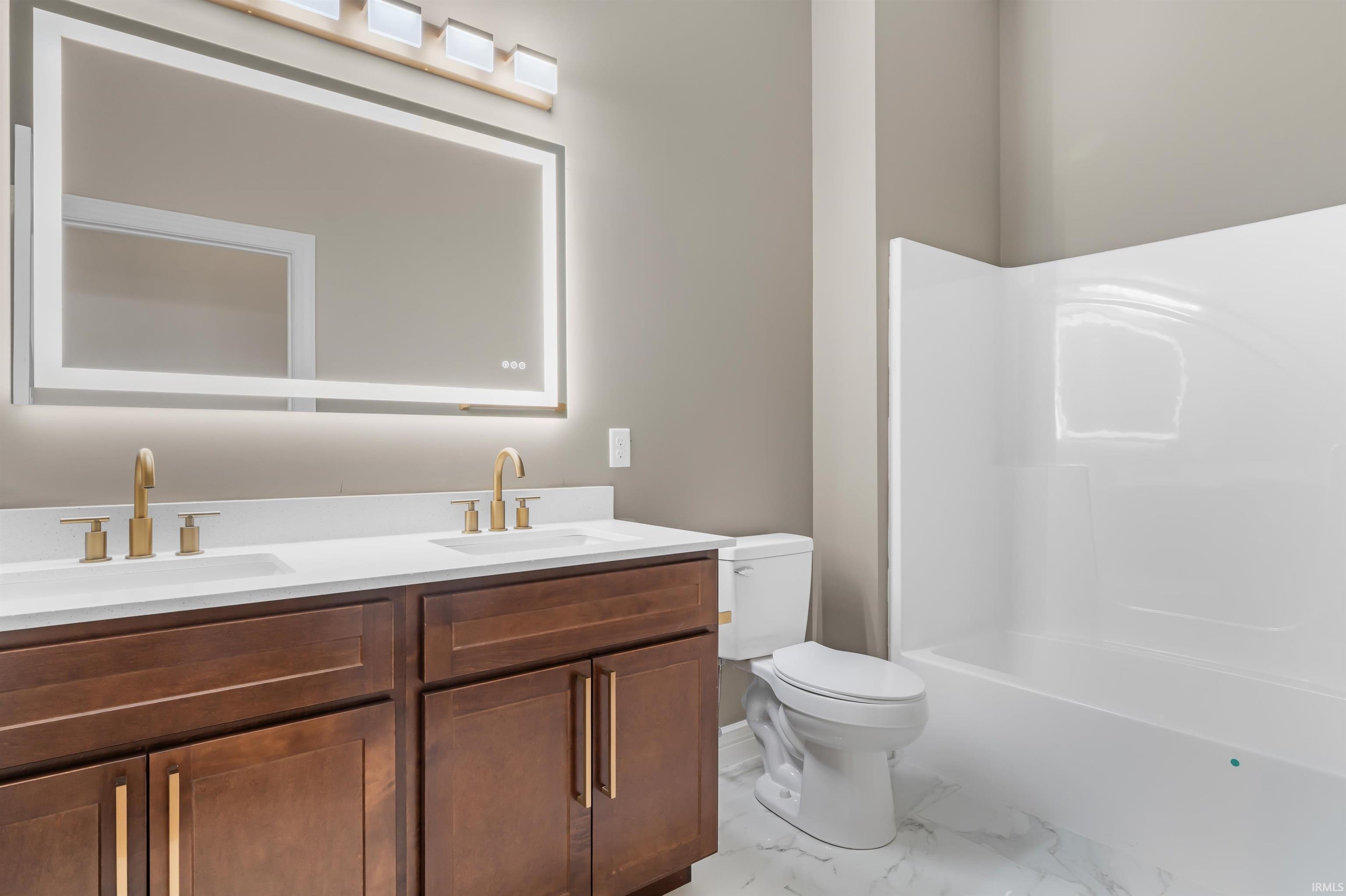 Bathroom with double vanity, shower / bath combination, and light marble finish floors