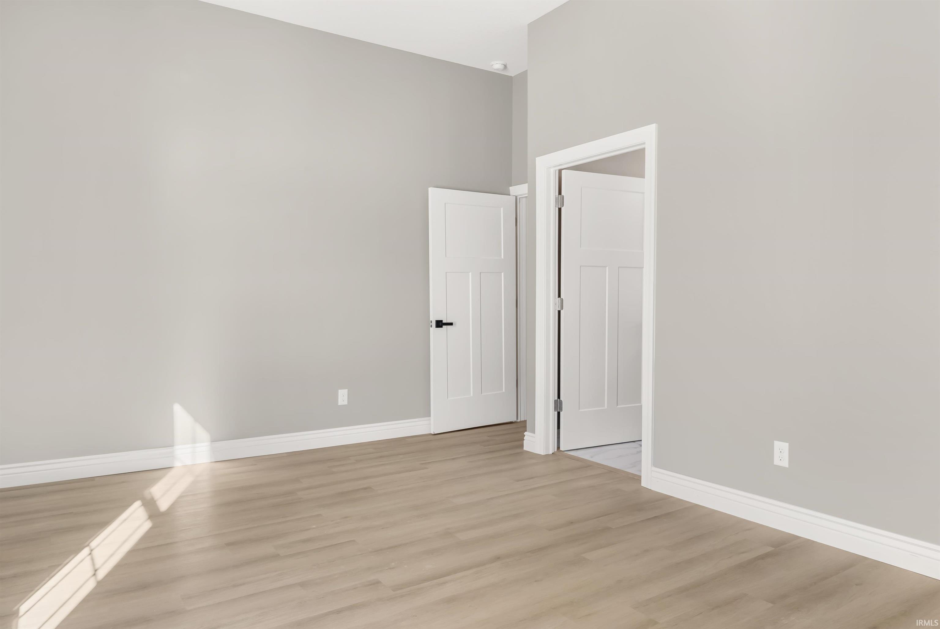 Empty room with light wood-style flooring and a high ceiling