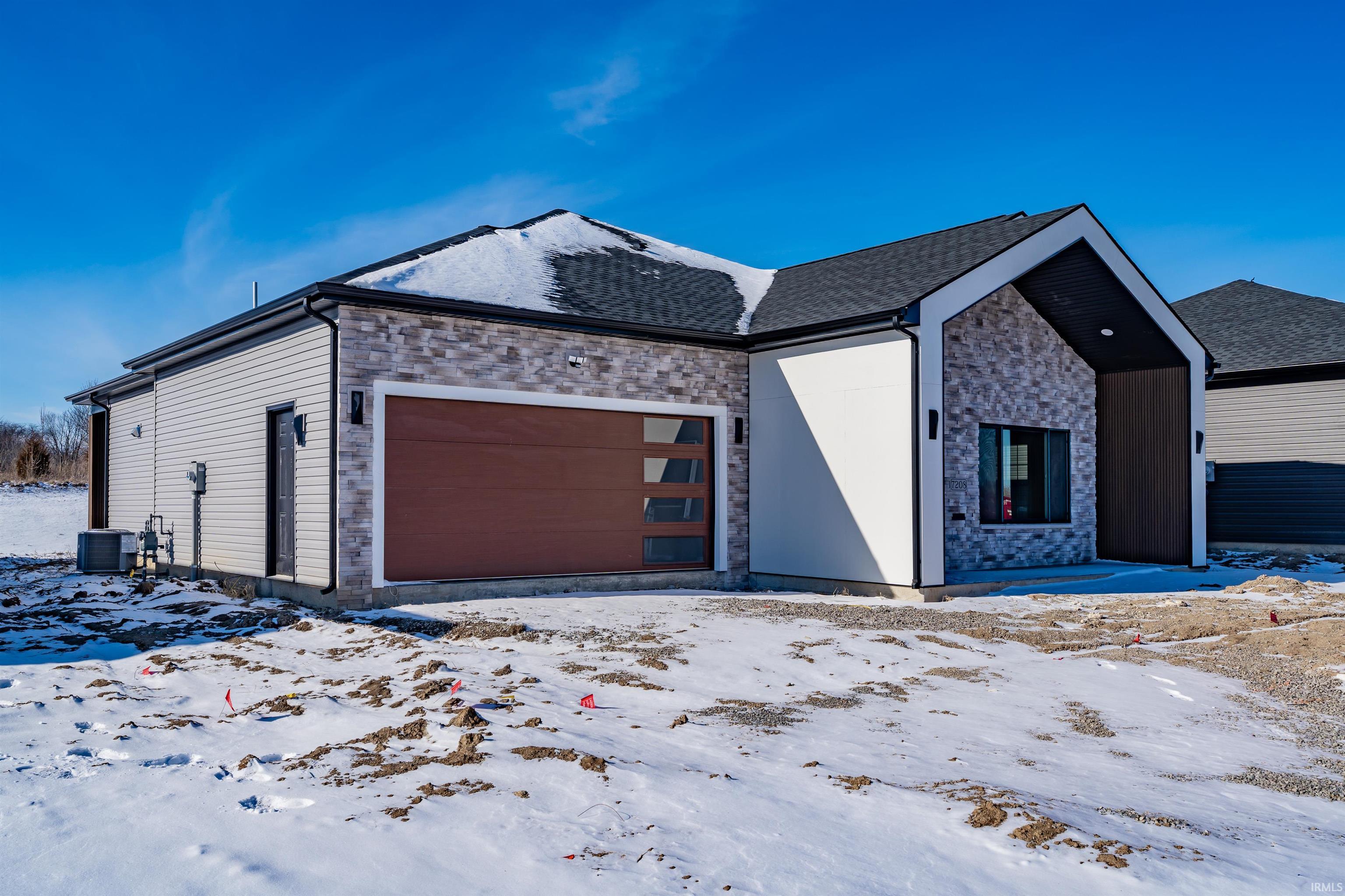 View of front of house with stone siding and an attached garage