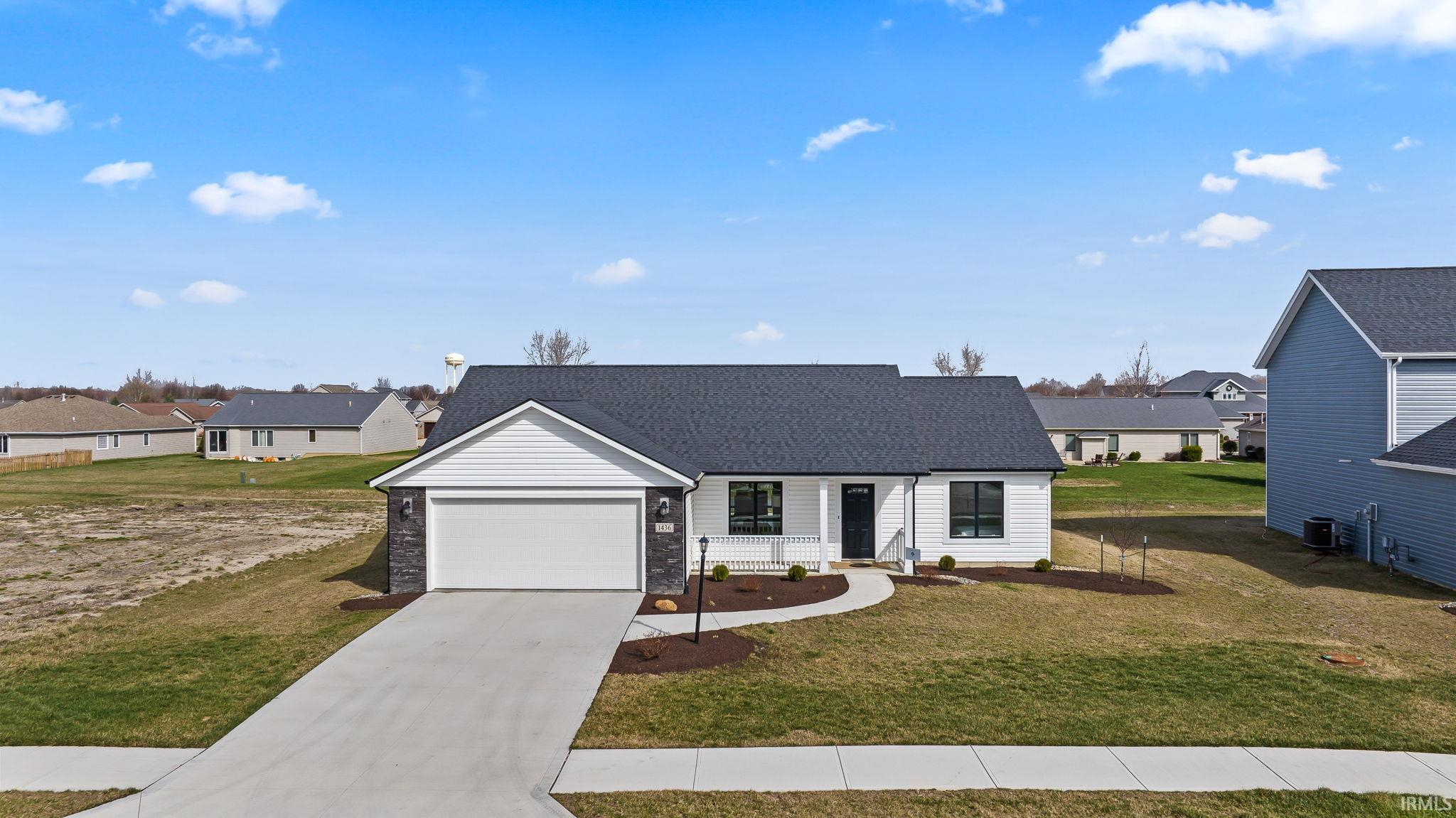 View of front of house featuring a residential view, a front yard, concrete driveway, and an attached garage