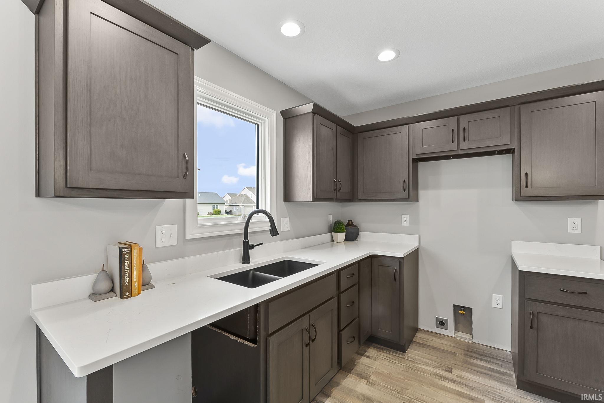 Kitchen with light wood-style floors, recessed lighting, dark wood finish cabinets, and light stone countertops