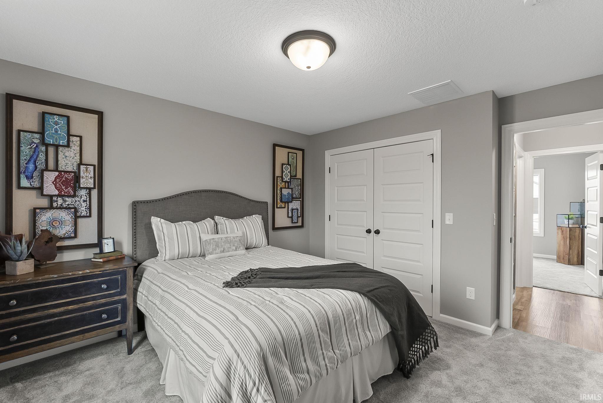 Bedroom featuring light colored carpet, a closet, and a textured ceiling