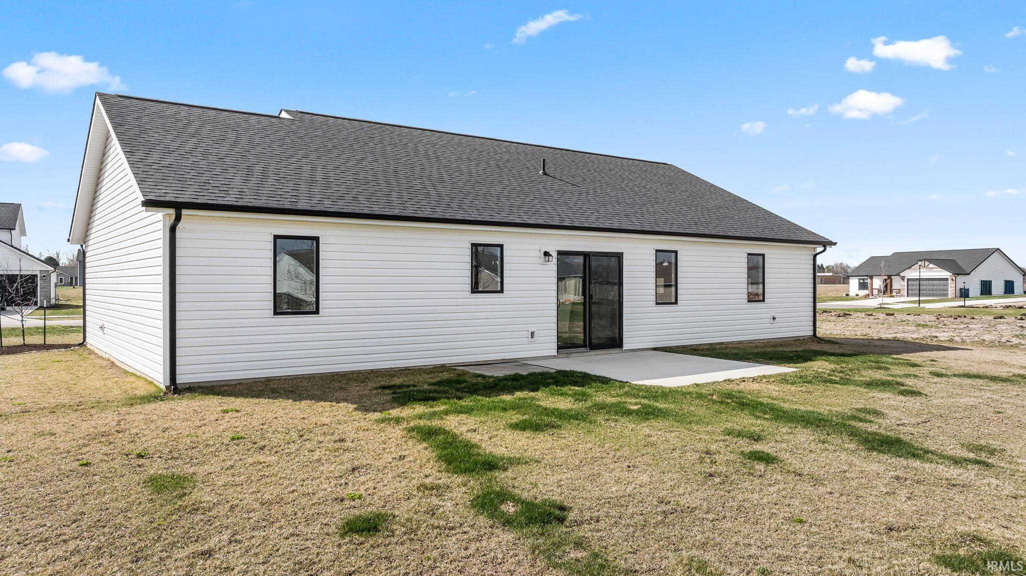 Rear view of property featuring a patio area, a shingled roof, and a yard