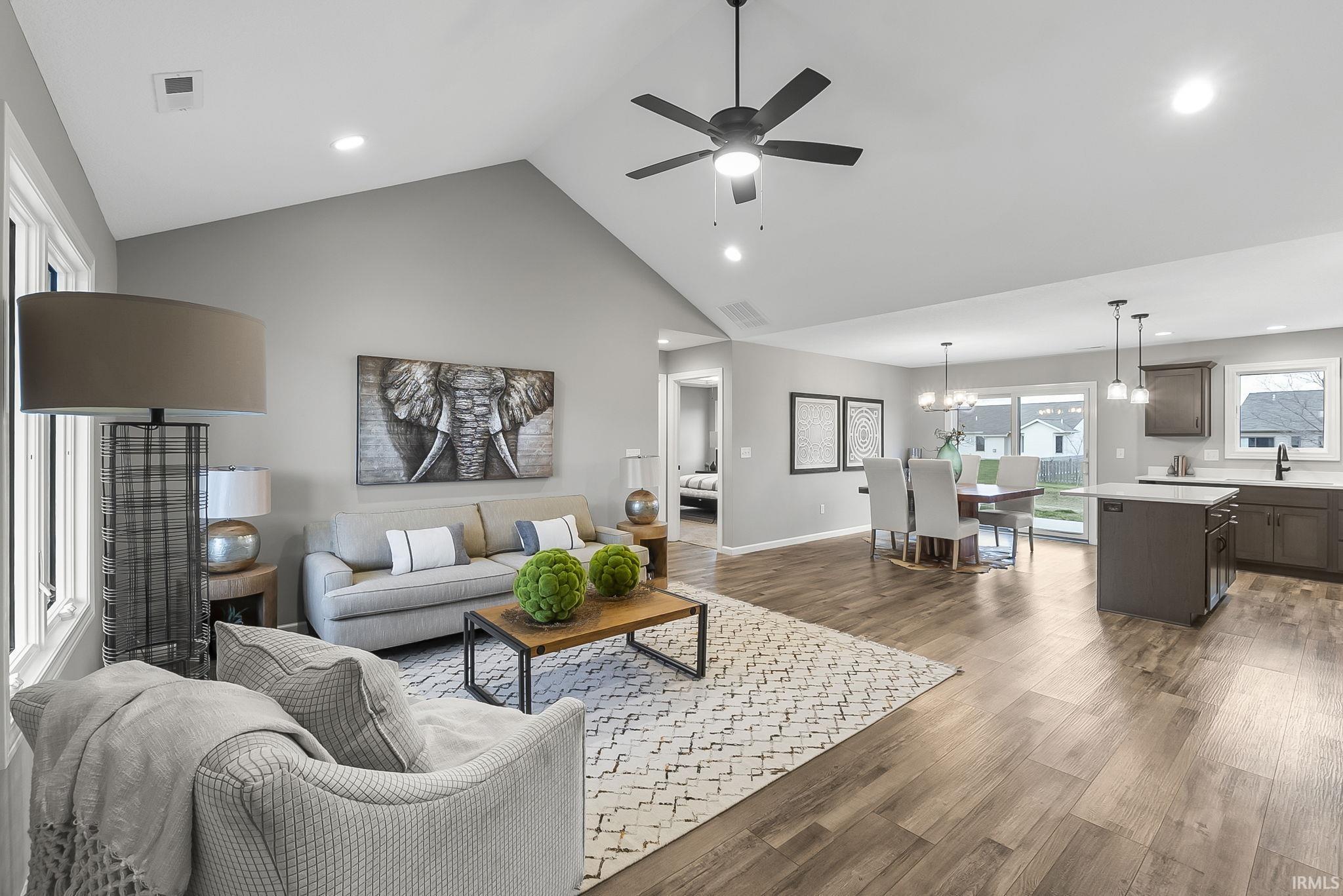 Living room with a ceiling fan, dark wood-style floors, a high ceiling, and suspended lighting