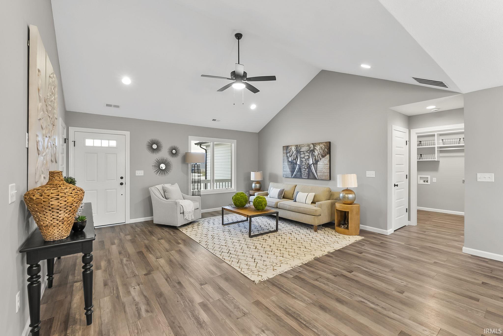 Living room featuring a ceiling fan, wood finished floors, recessed lighting, and a high ceiling