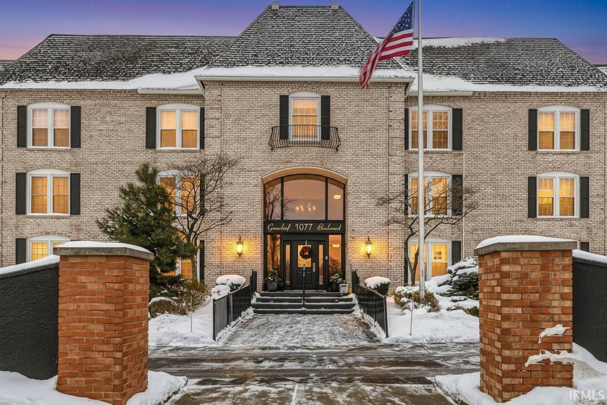 Snow covered property with brick siding