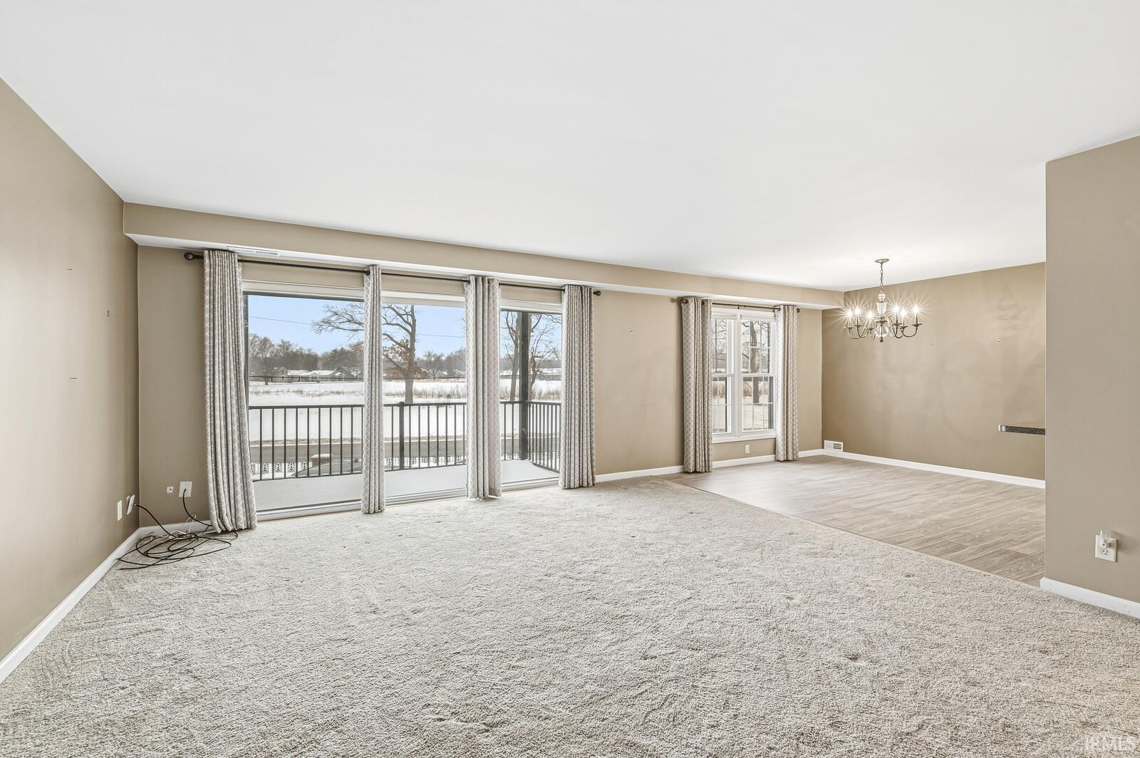 Carpeted spare room with baseboards and hanging lights
