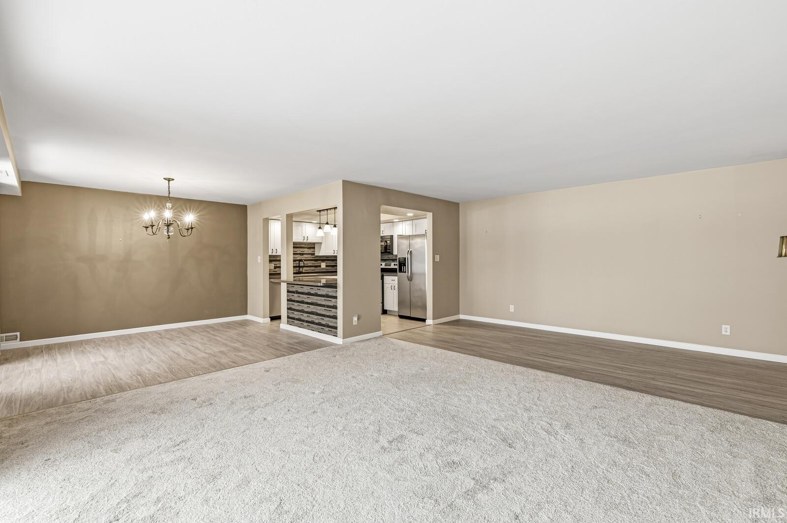 Unfurnished living room featuring carpet and hanging lights