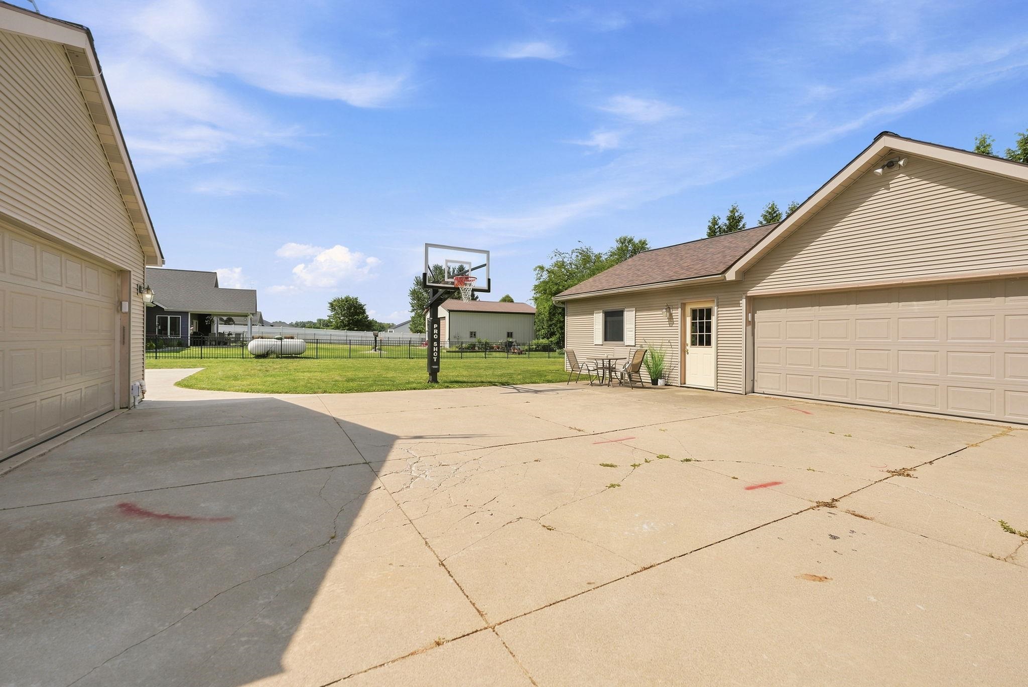 Spacious concrete driveway featuring a basketball hoop