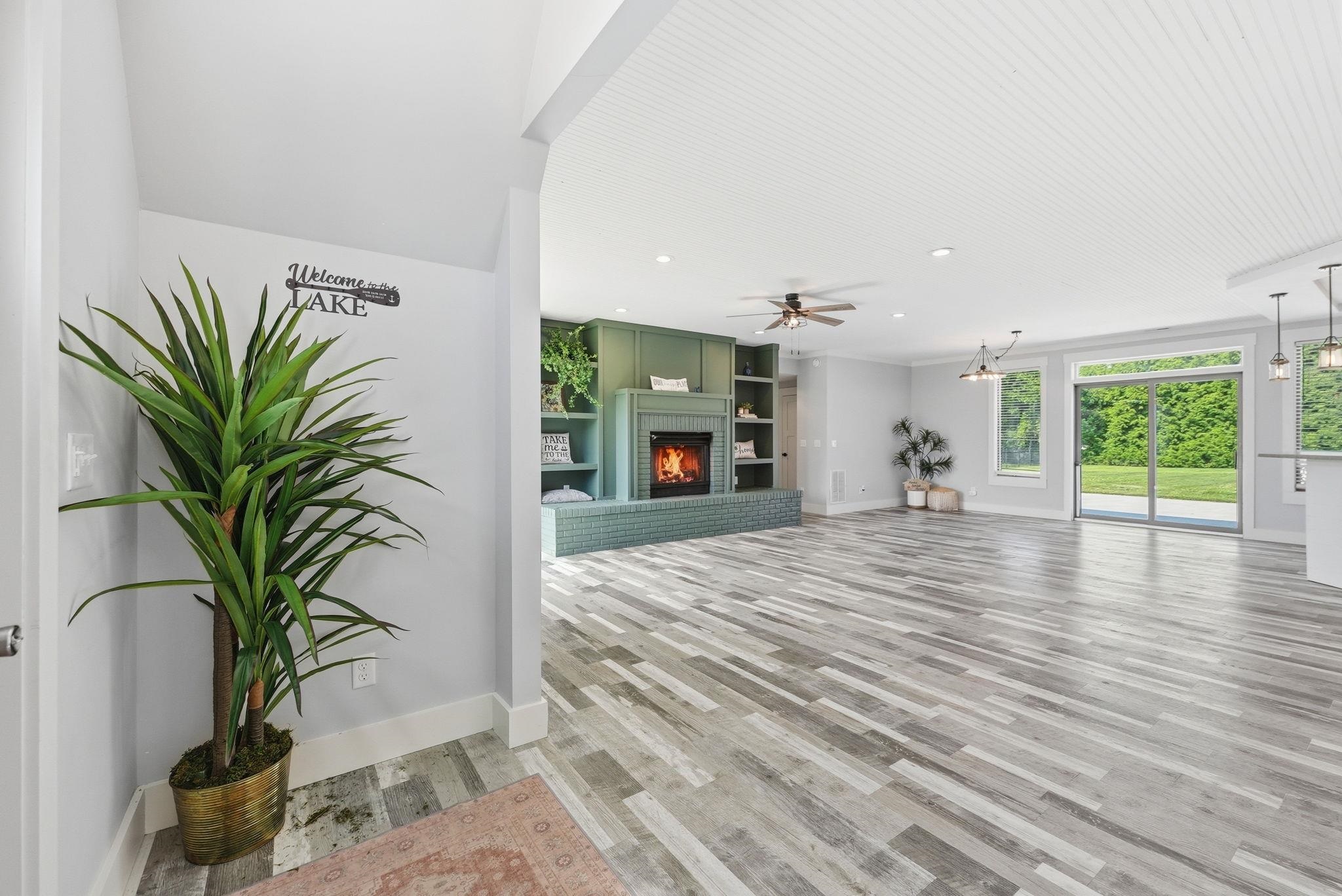 Spacious living area featuring plank wood-finish flooring, a fireplace with built-in cabinetry, and a ceiling fan
