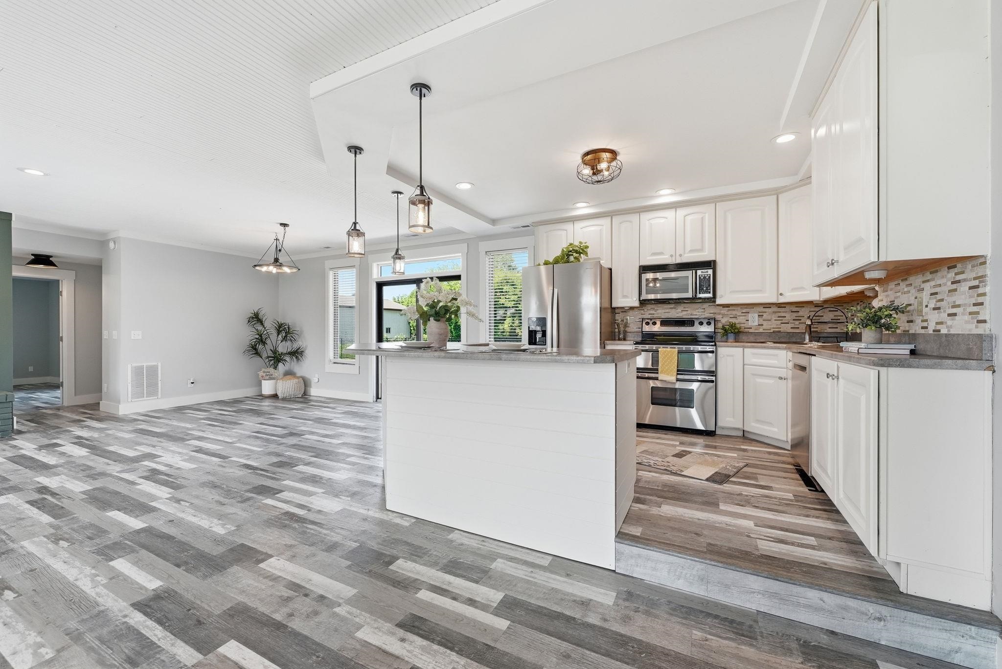 Modern kitchen featuring white cabinetry, stainless steel appliances, and a mosaic tile backsplash