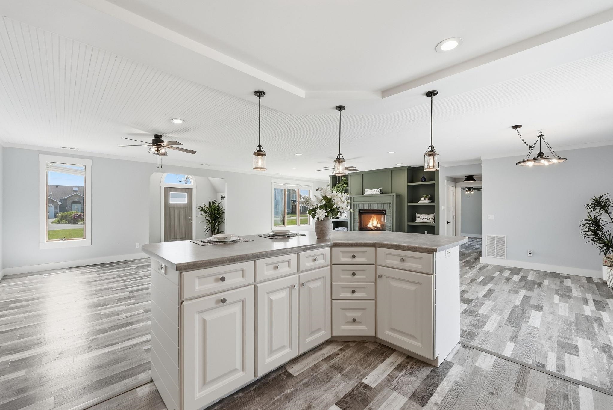 Open-concept living area featuring a central kitchen island with light countertops, wood-finish flooring, a beadboard ceiling, and recessed lighting