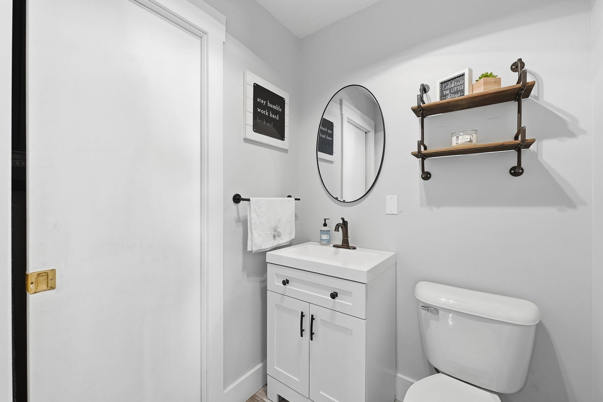 Bathroom featuring a white vanity with integrated sink, bronze-finish faucet, and a black-framed oval mirror