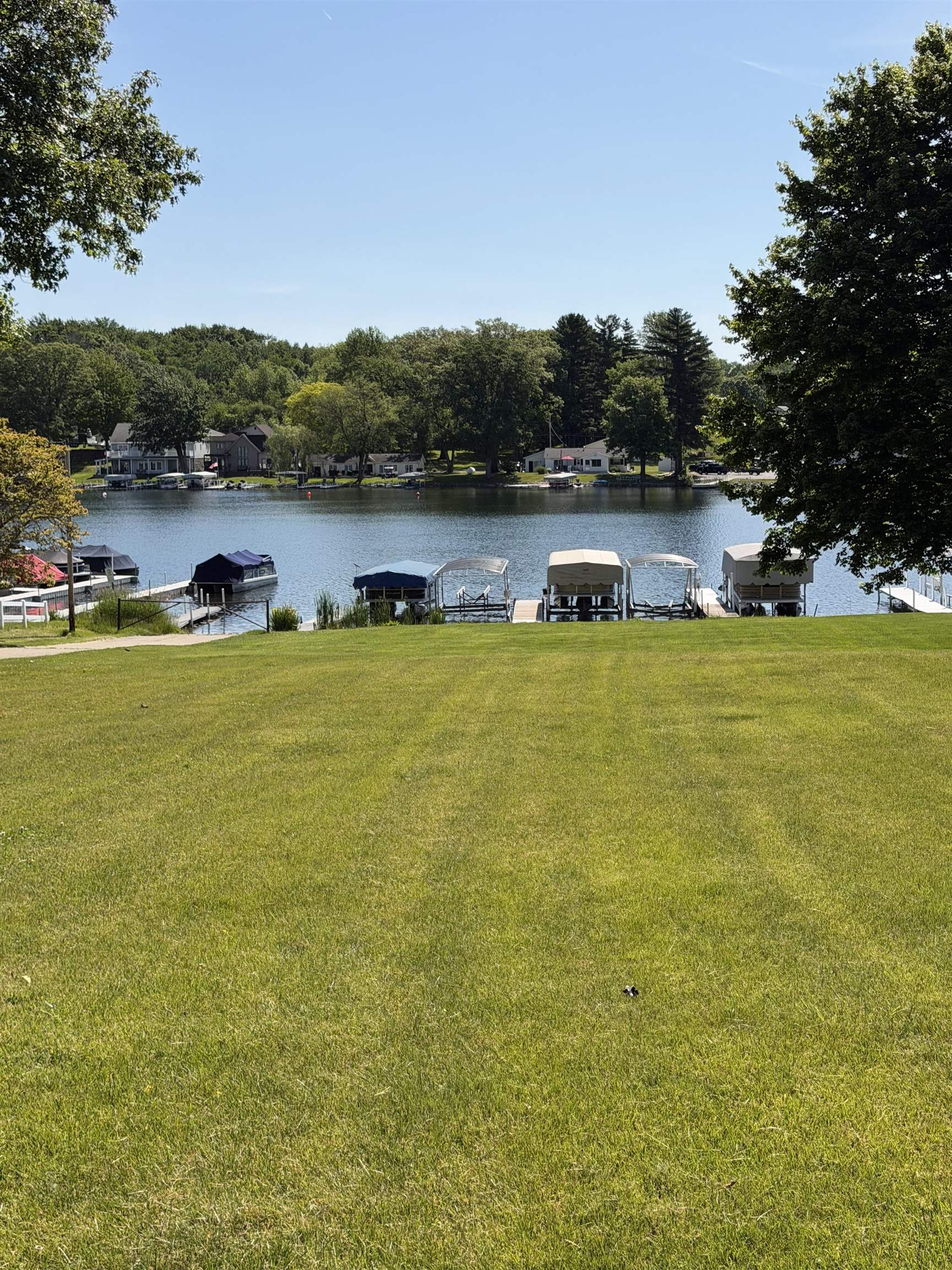 Expansive association lawn descending to a large lake with multiple boat slips and docks
